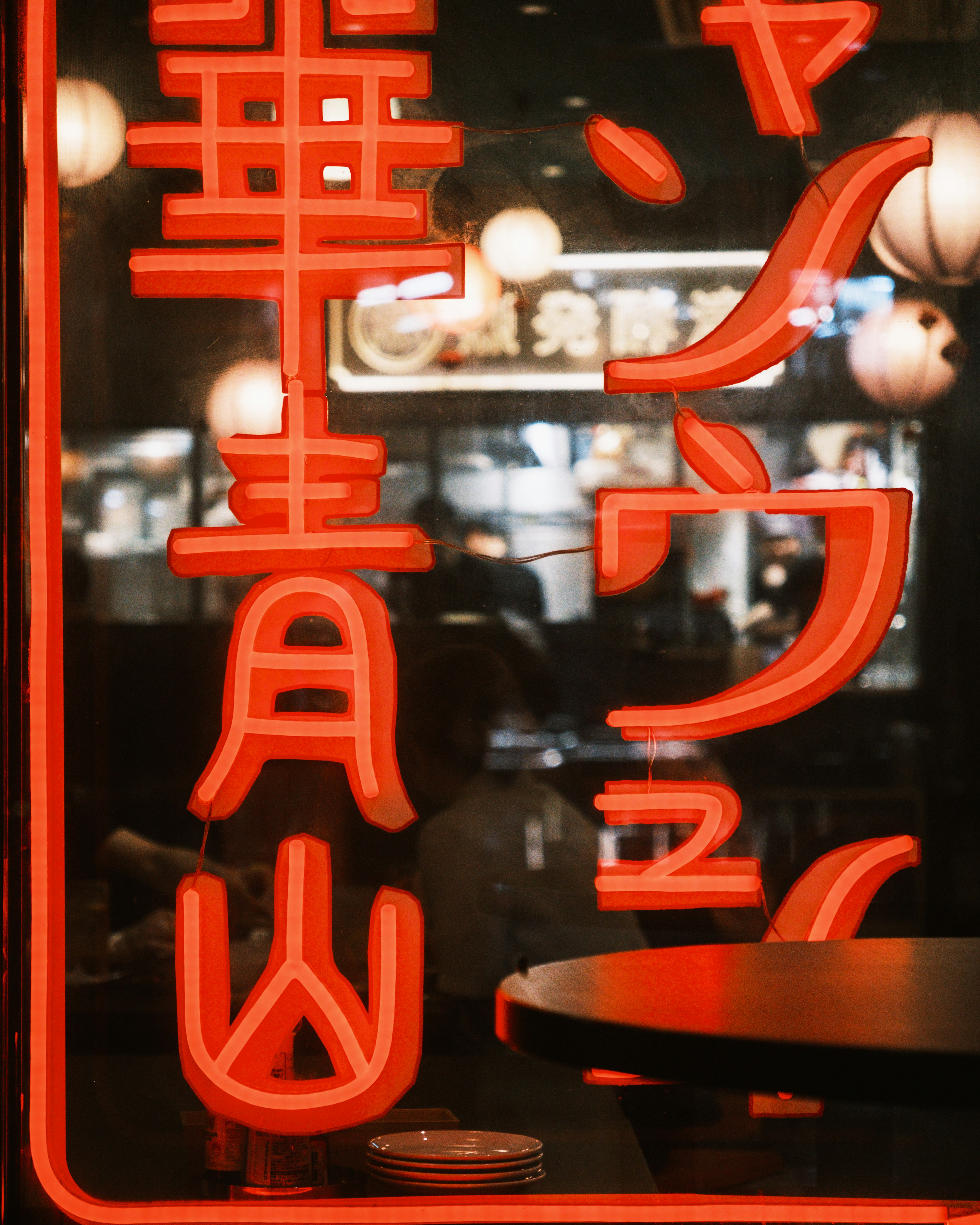 Red neon sign with characters and blurred background lights