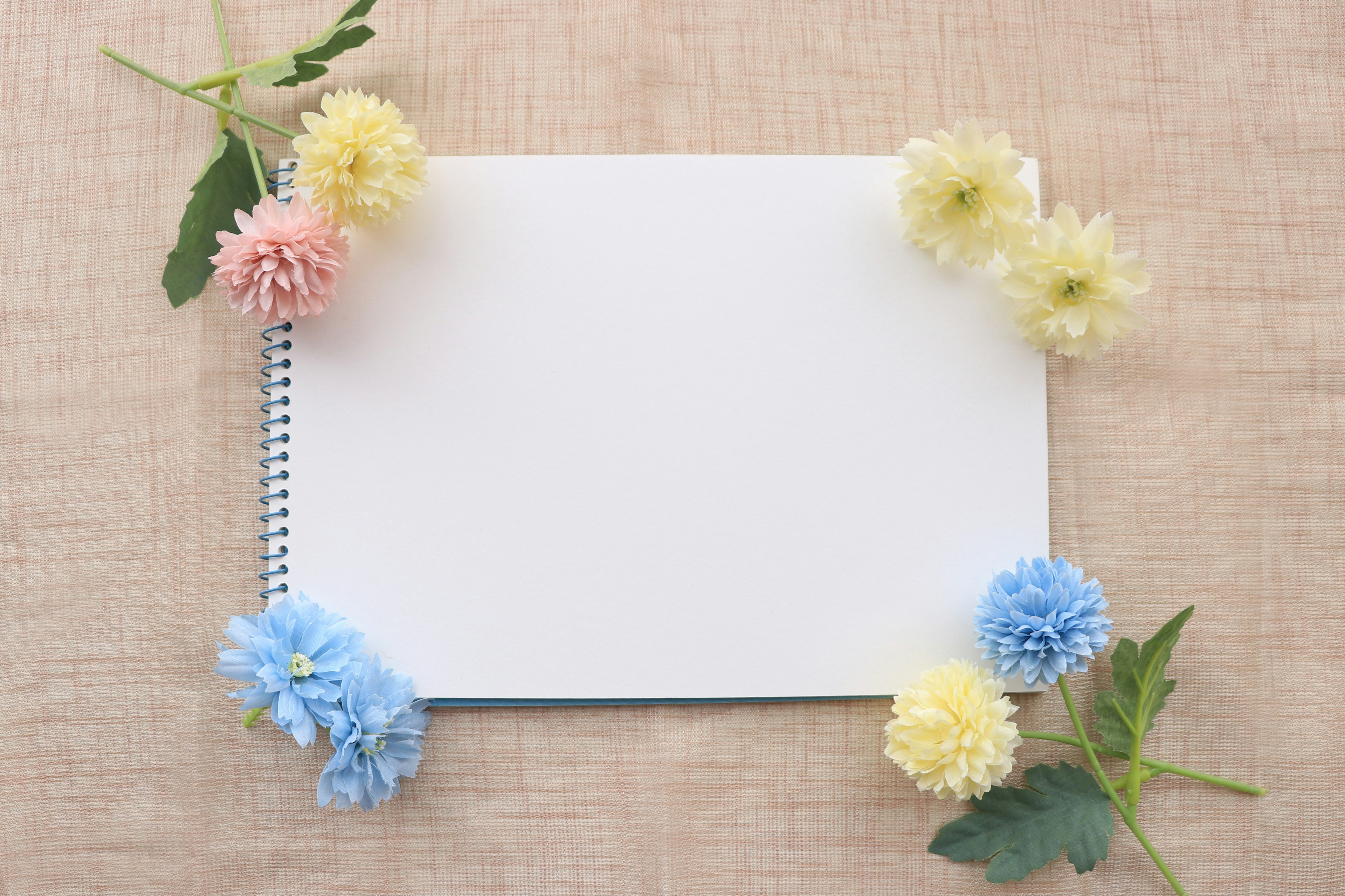 Ein leeres Notizbuch umgeben von bunten Blumen auf einem strukturierten Hintergrund