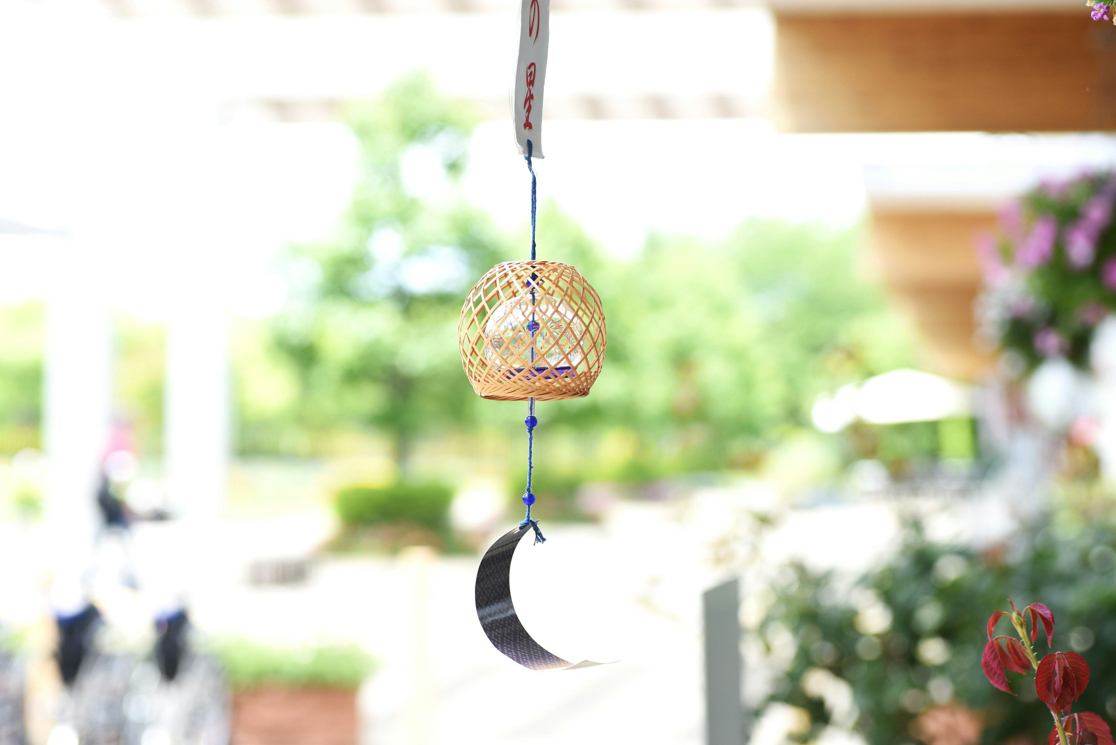 A small golden wind chime hanging with a crescent moon decoration against a green background