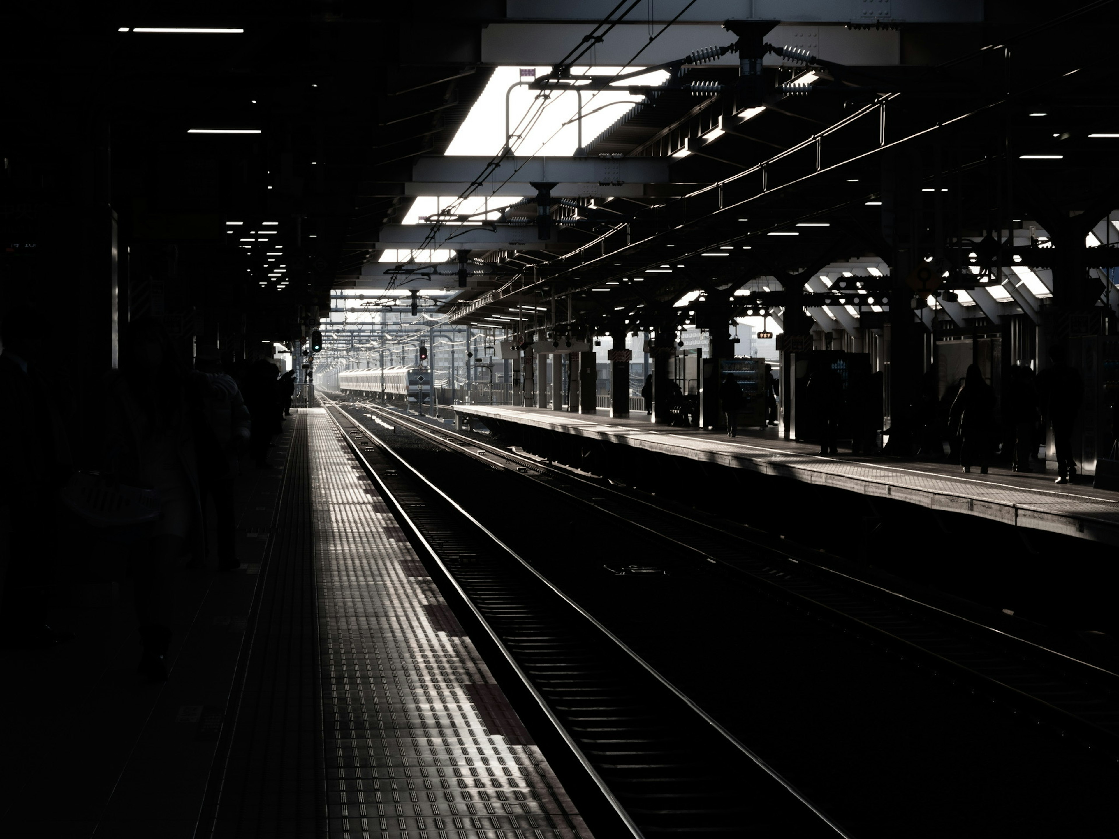 Dimly lit train station platform with tracks