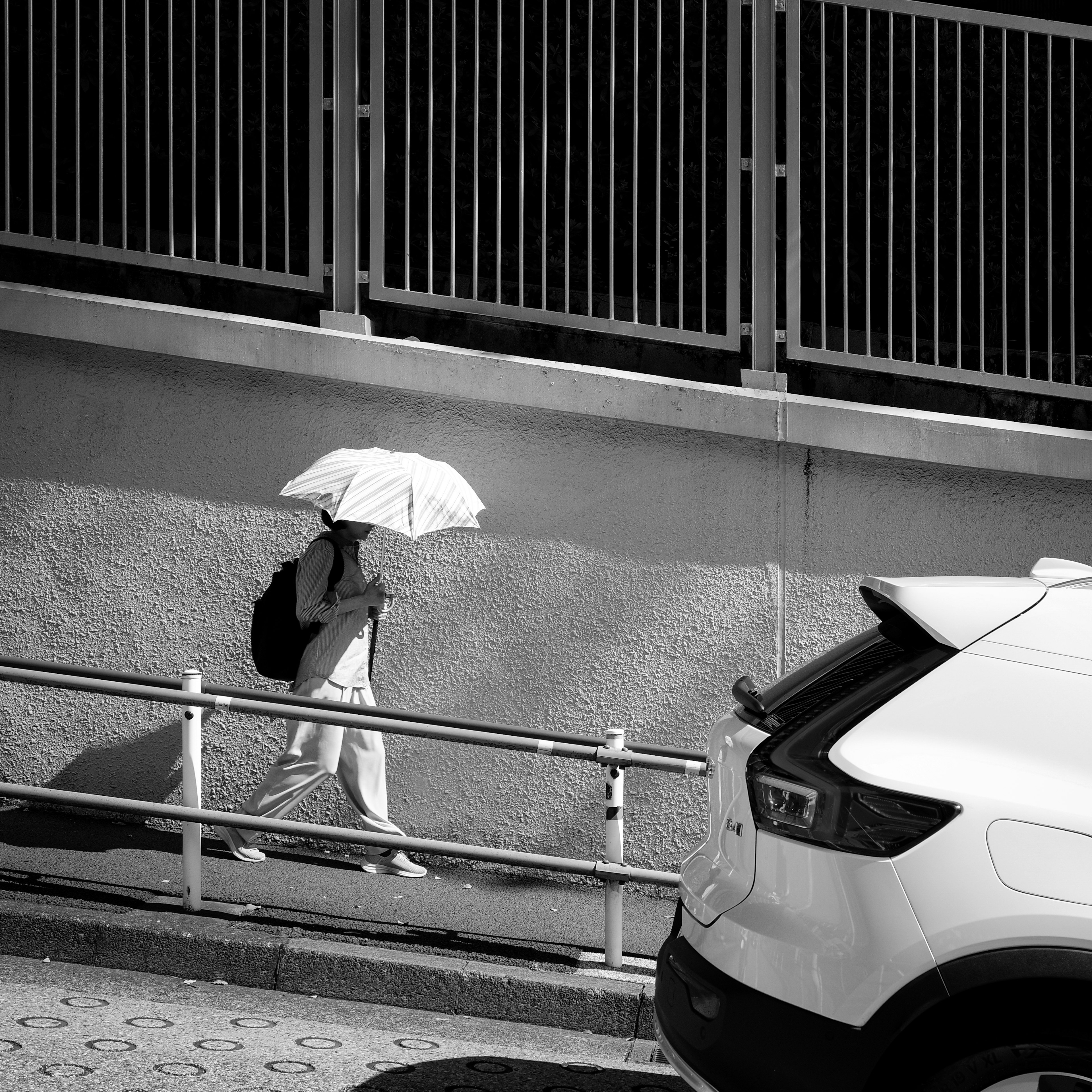 Eine Person mit einem weißen Regenschirm in einer schwarz-weißen Stadtlandschaft