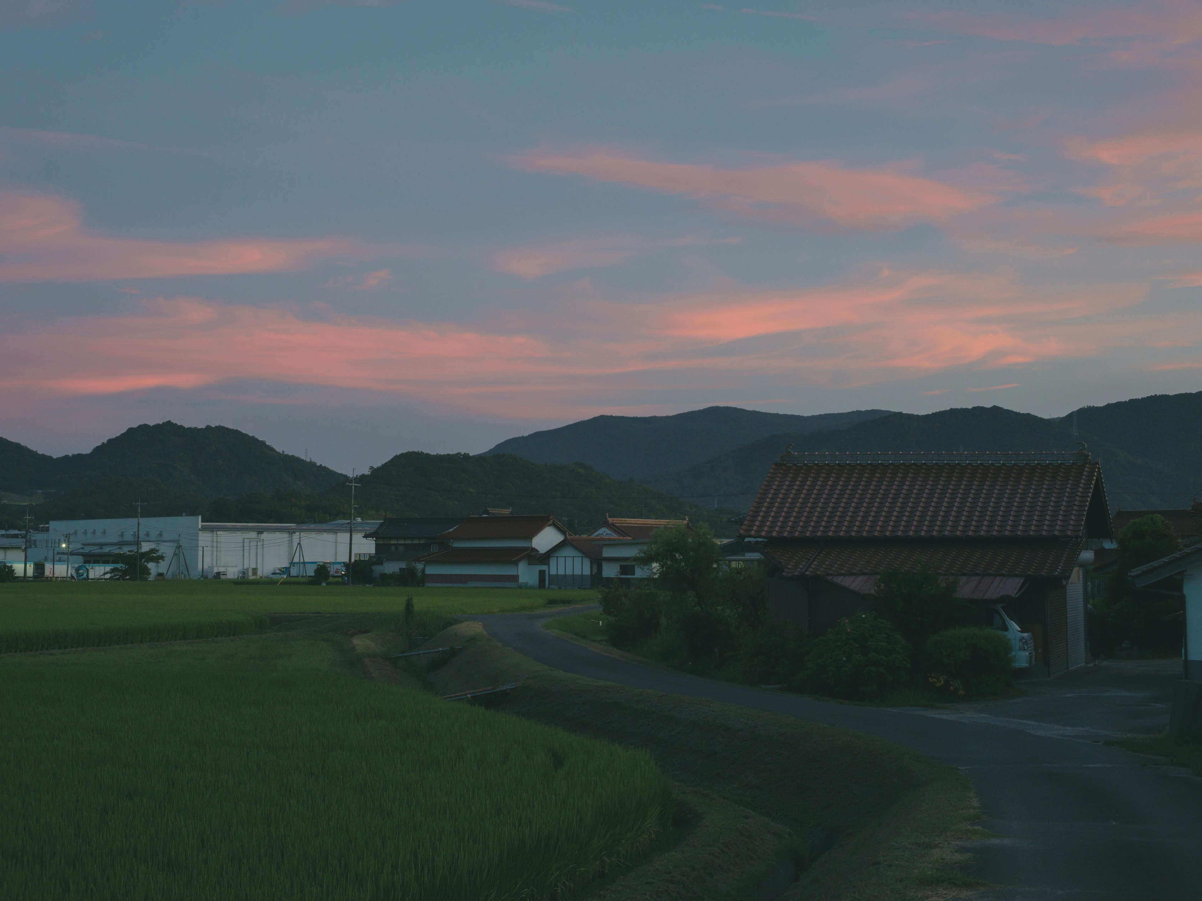 ทิวทัศน์ชนบทที่มีบ้านในขณะที่พระอาทิตย์ตก