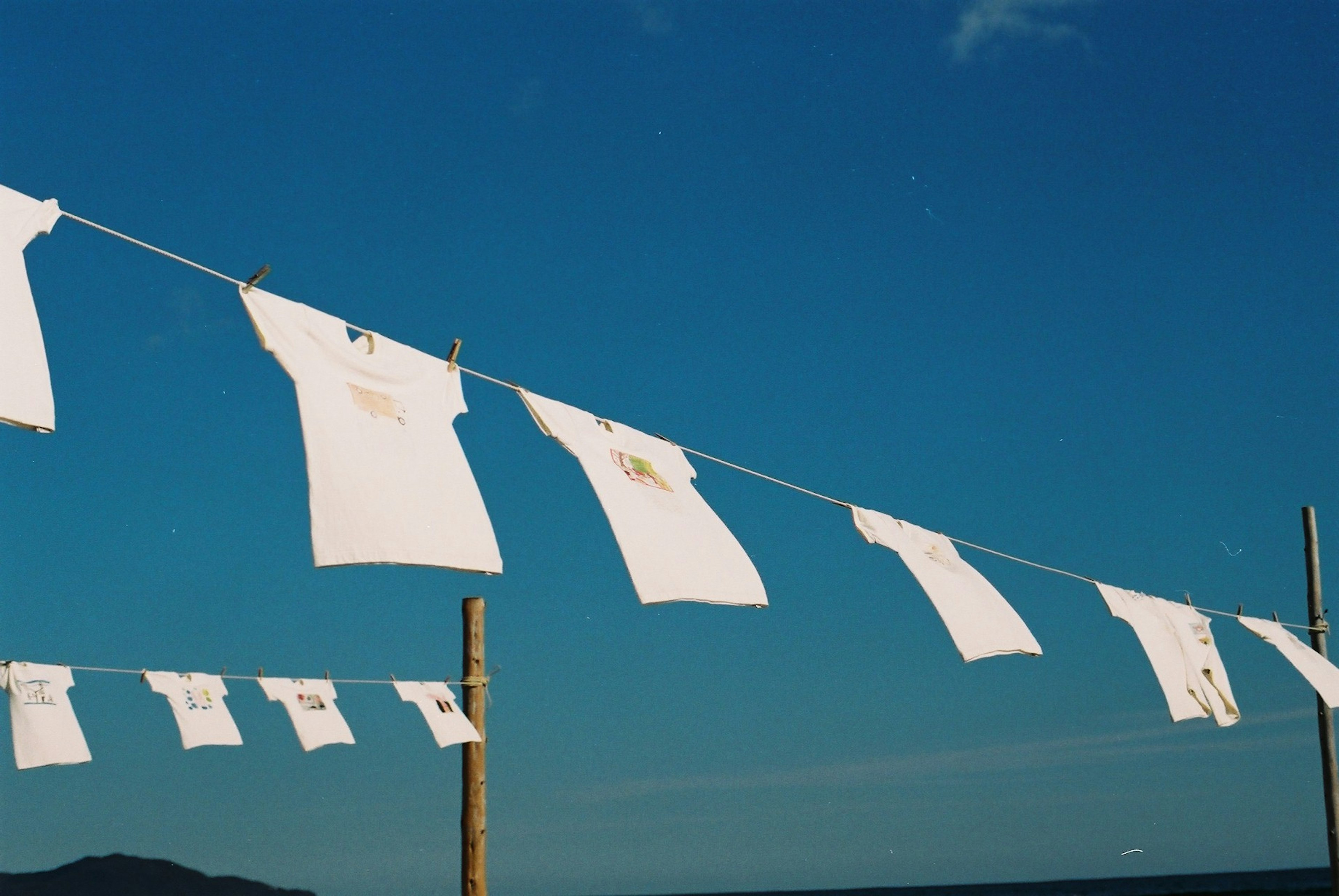 T-shirts blancs suspendus sur une corde à linge sous un ciel bleu