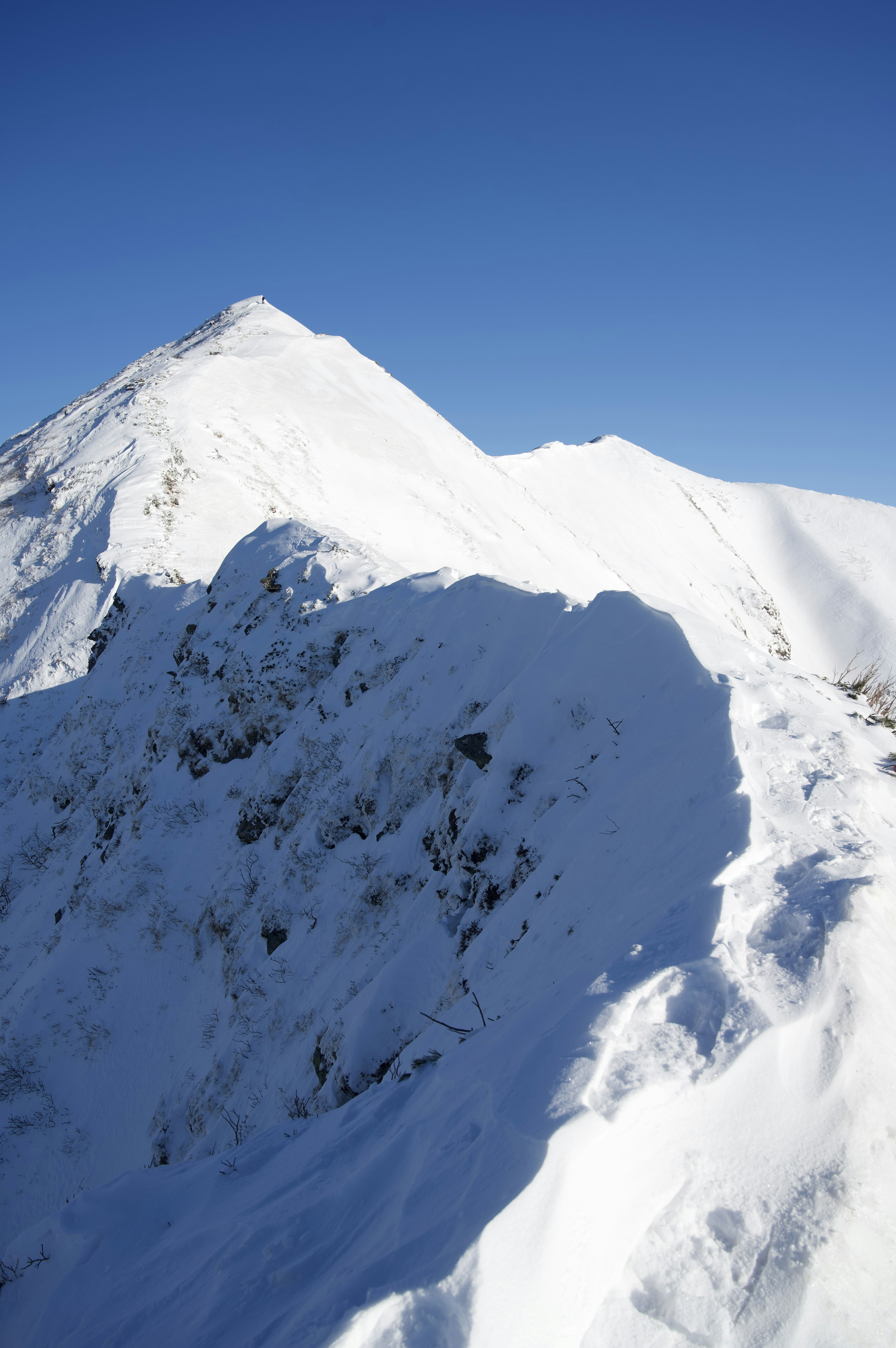 Paisaje montañoso cubierto de nieve con cielo azul claro