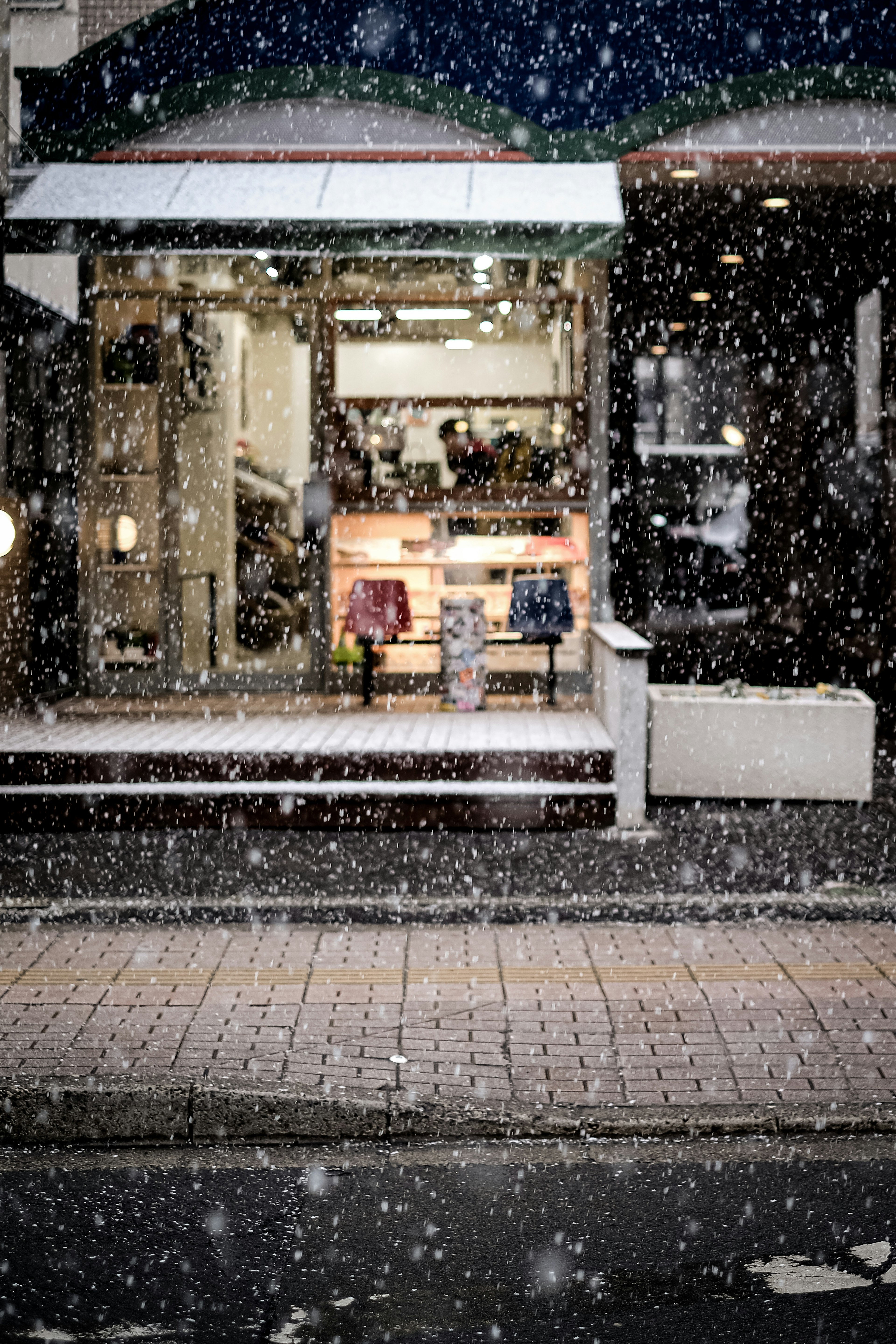 雪の降る中の店舗の外観と温かい光