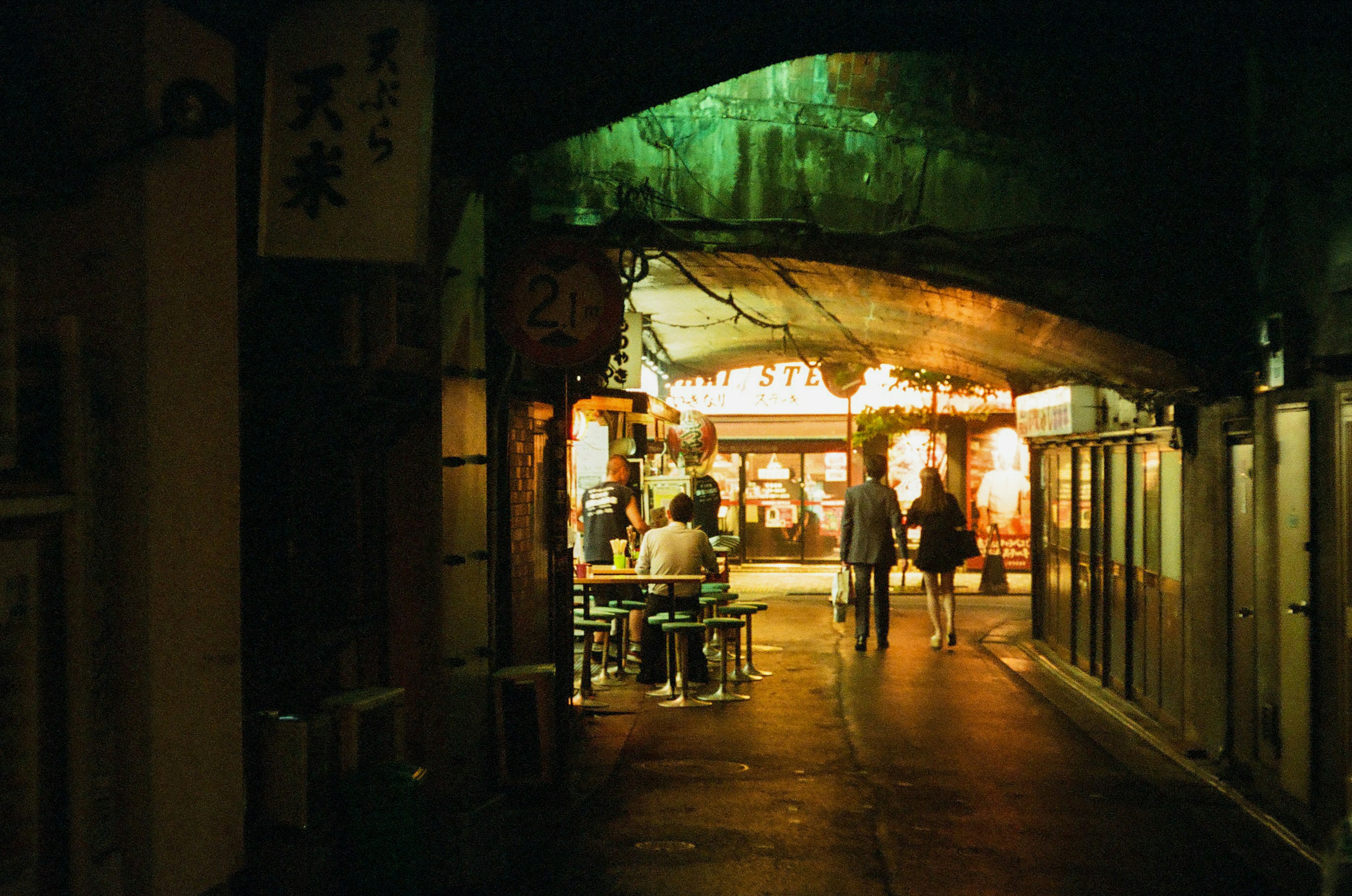 People walking in a night street with bright signs in an alley