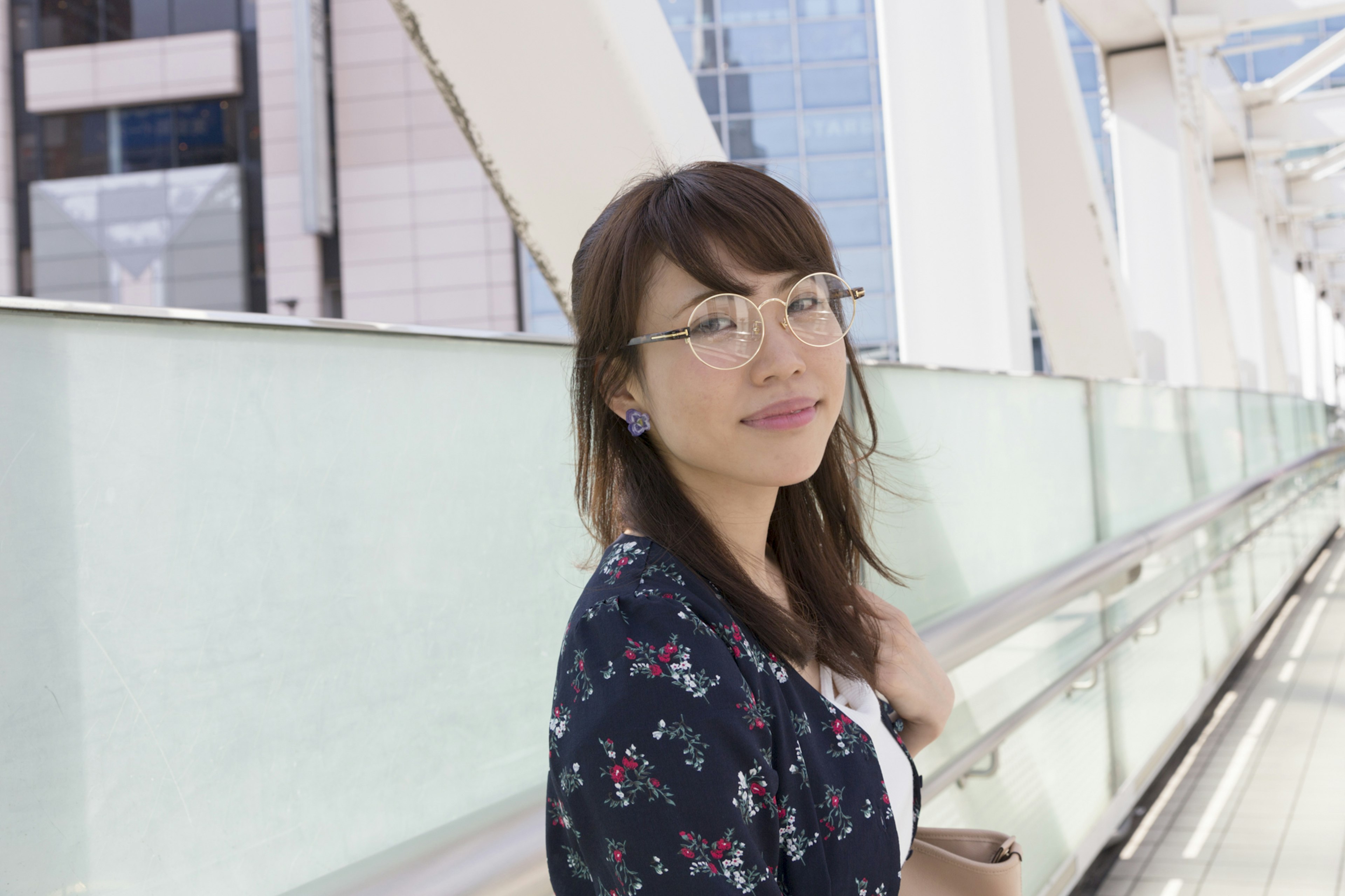 Una mujer con gafas sonriendo mientras camina en un entorno urbano