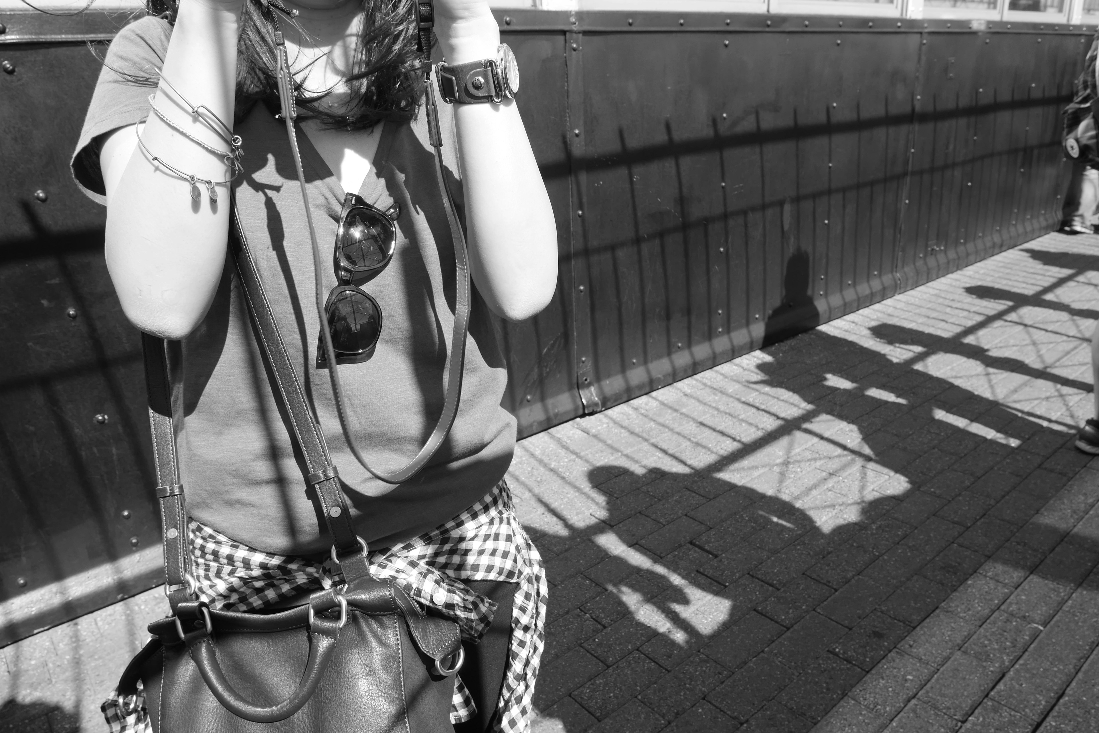 Black and white photo of a woman holding a camera with shadows on the ground