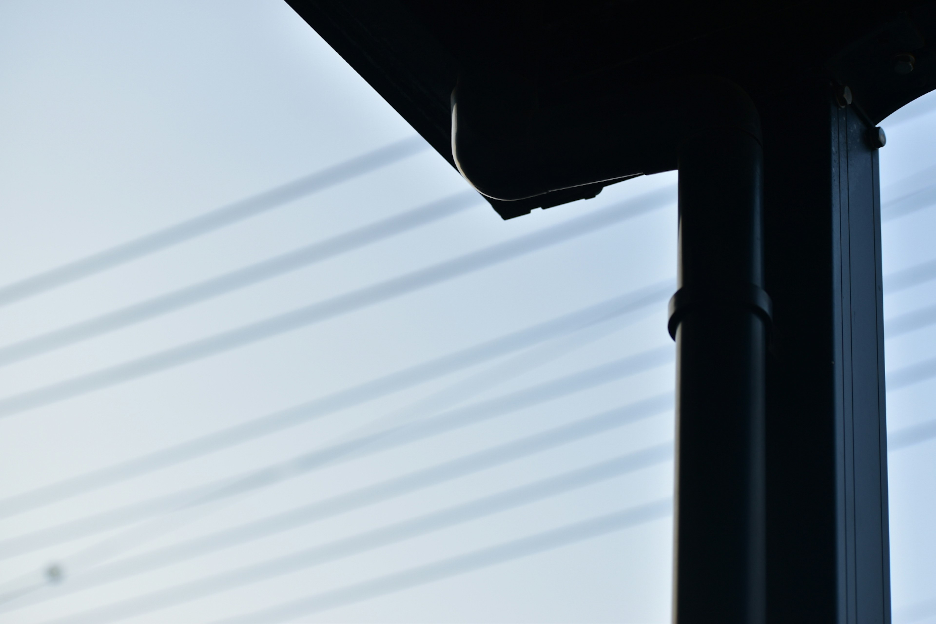 Silhouette of a utility pole with power lines against a blue sky