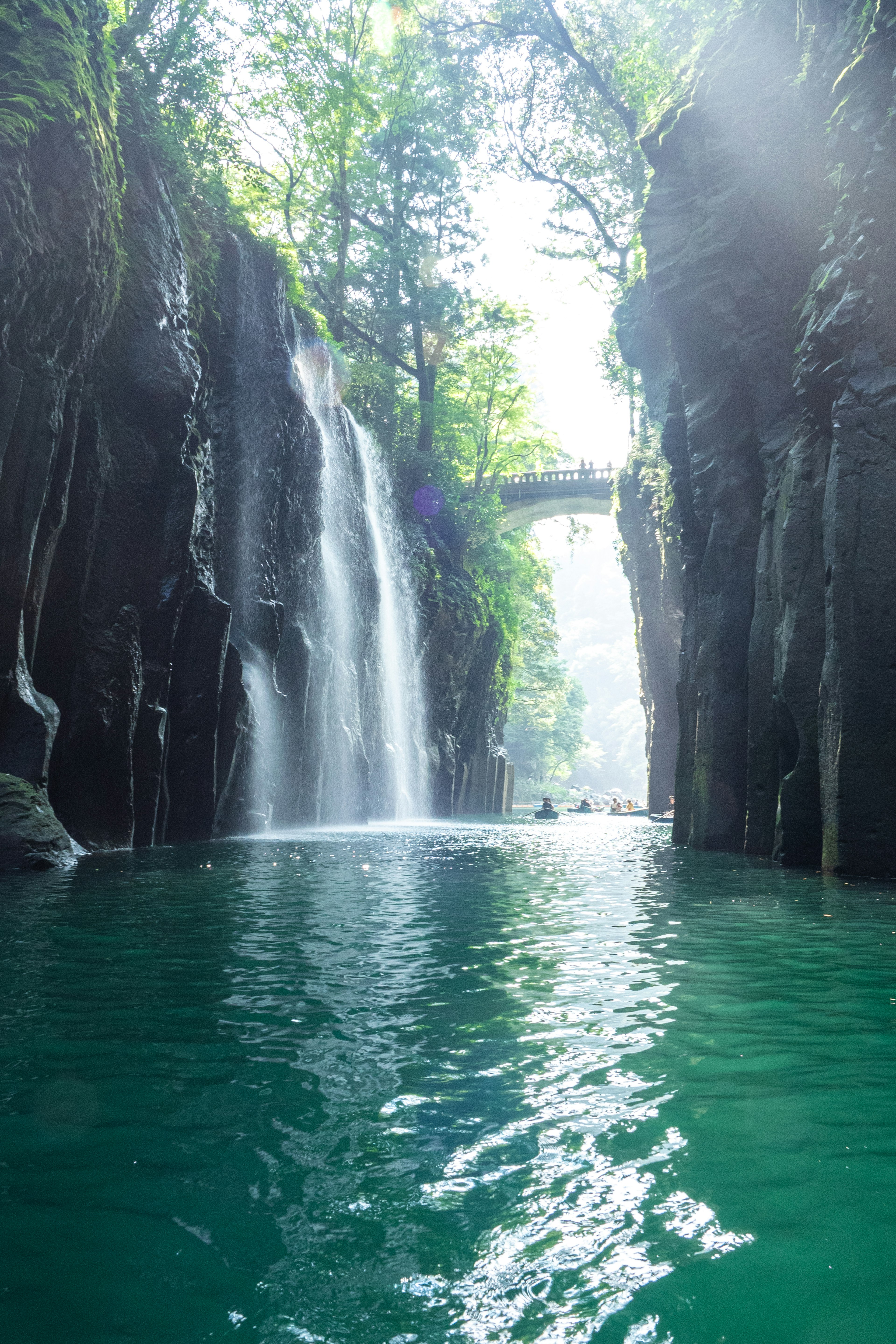 Paesaggio di canyon con cascate circondate da vegetazione riflessi sulla superficie dell'acqua