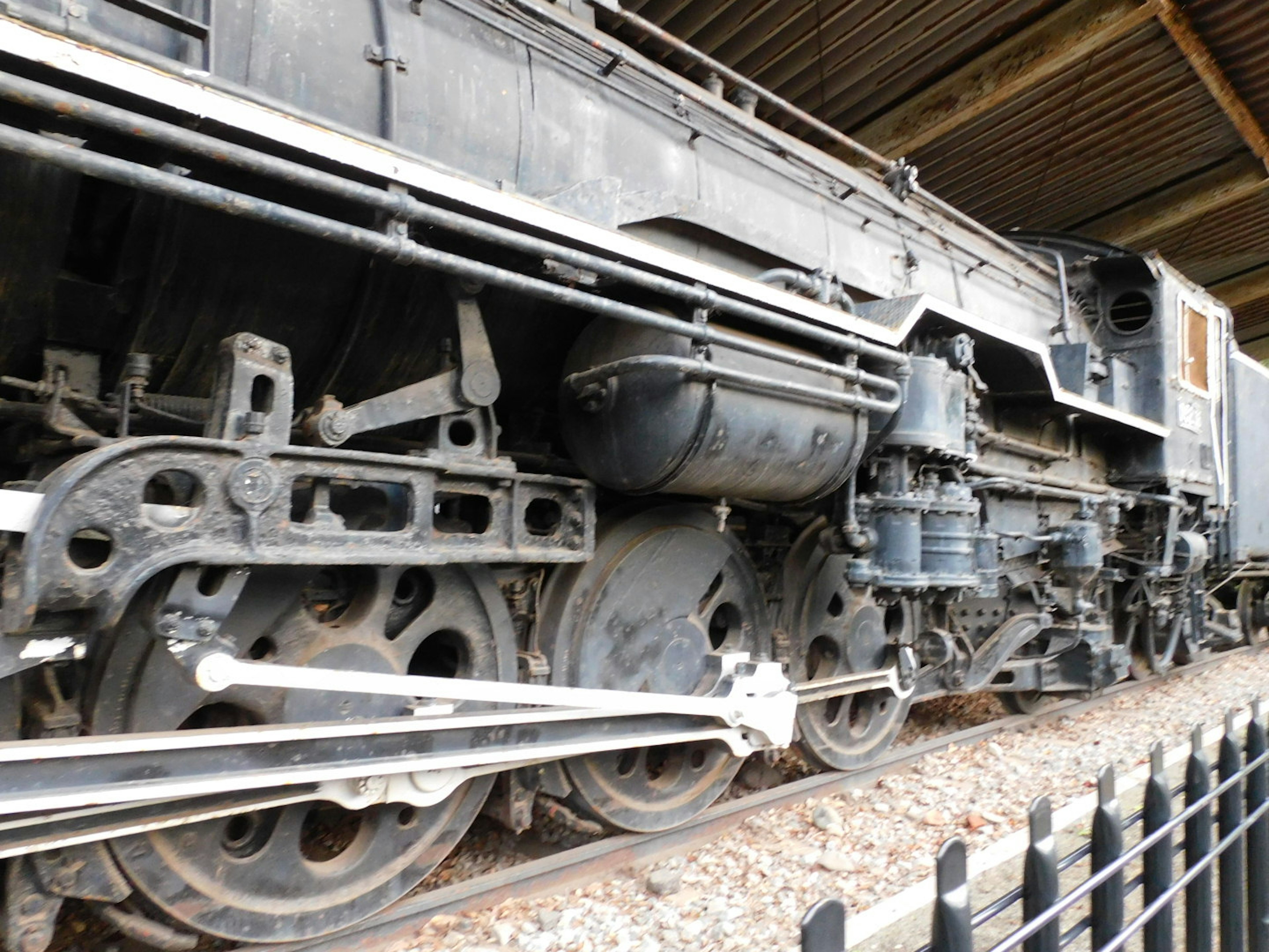 Vista lateral de una antigua locomotora de vapor mostrando sus ruedas y componentes mecánicos