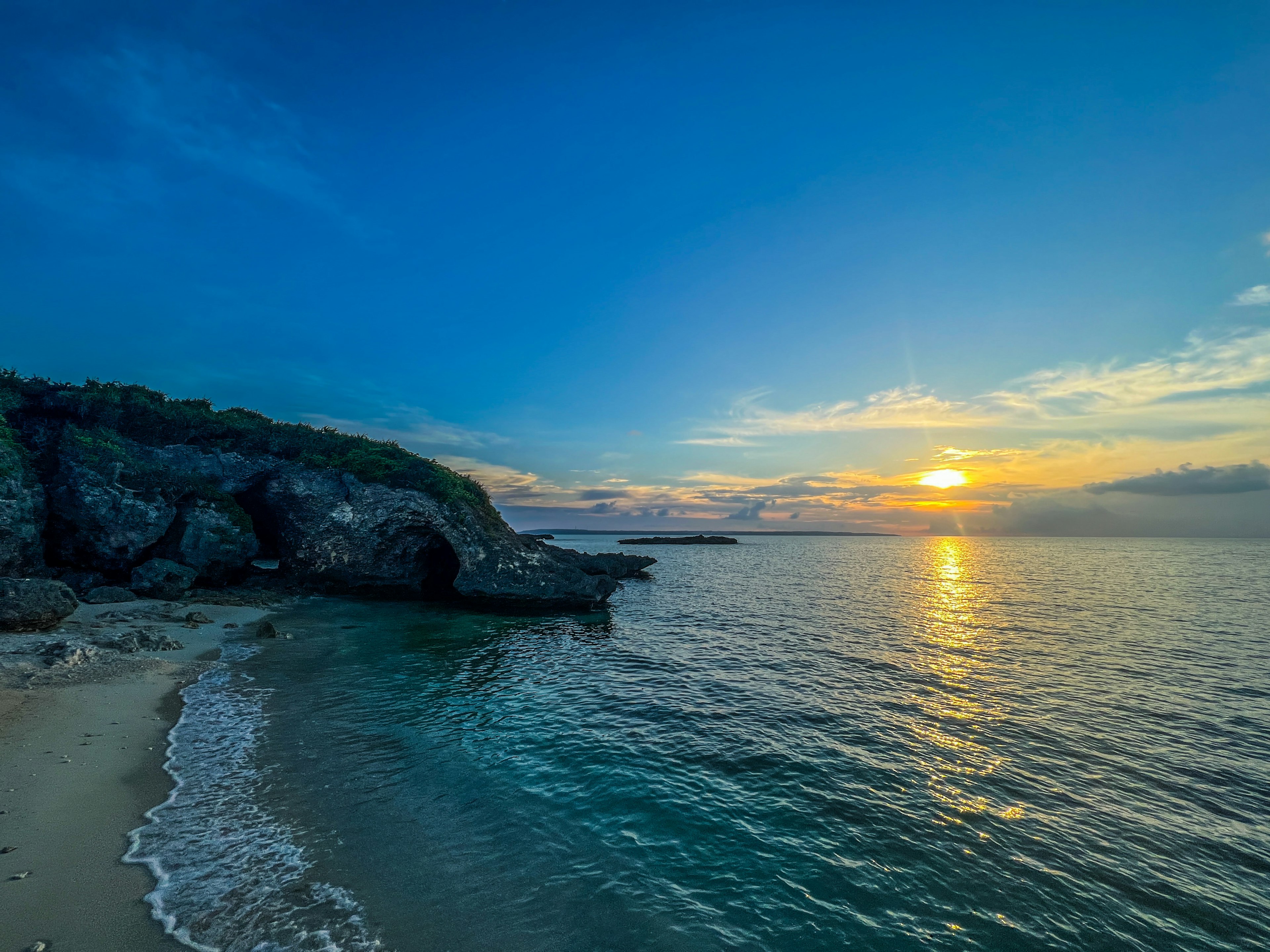 Pemandangan indah matahari terbenam di atas laut dengan garis pantai dan tebing yang terlihat