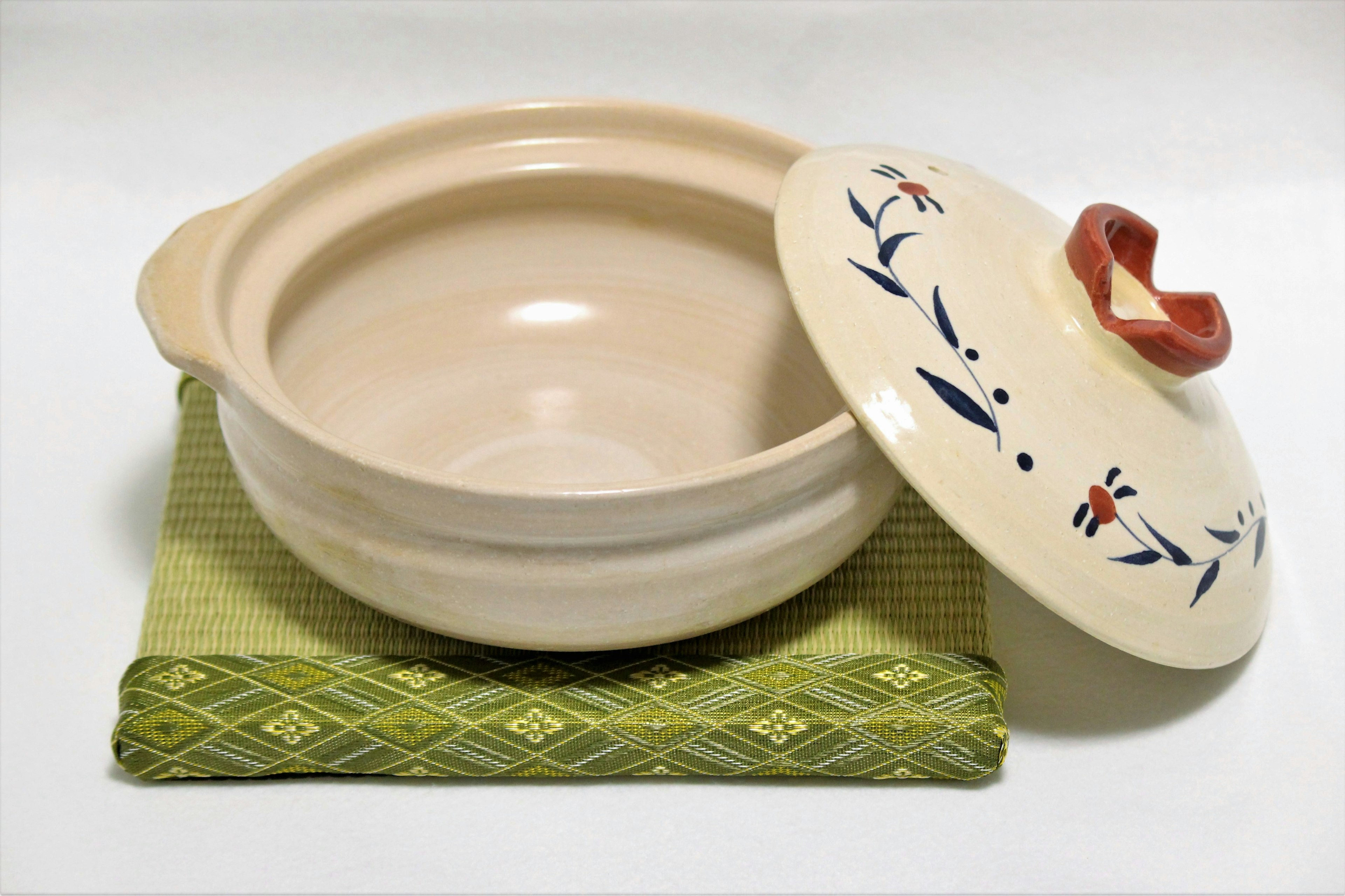 A white ceramic pot with a lid resting on a green cloth