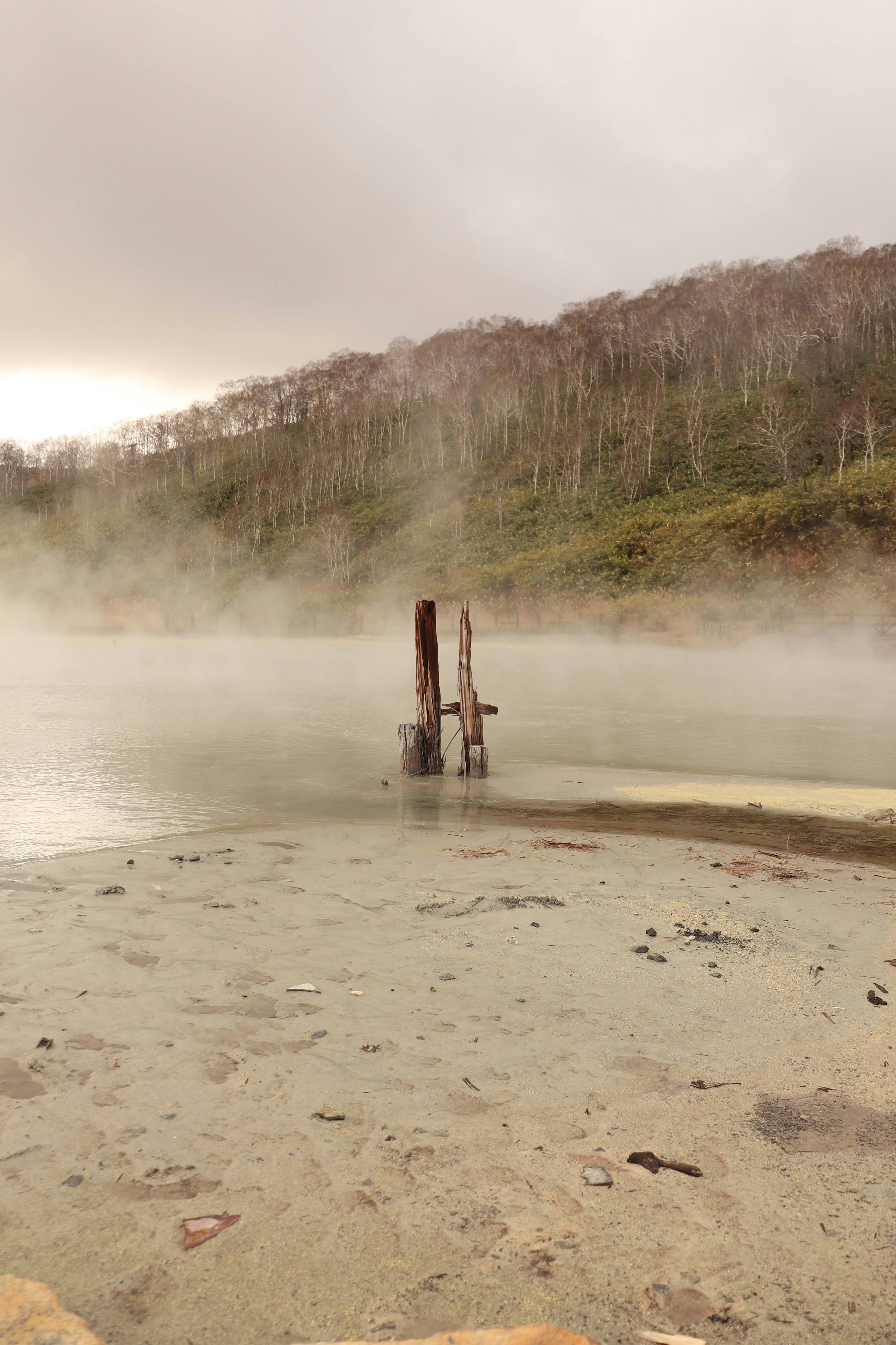 从温泉冒出的蒸汽的宁静湖泊风景 木栈道矗立在水中