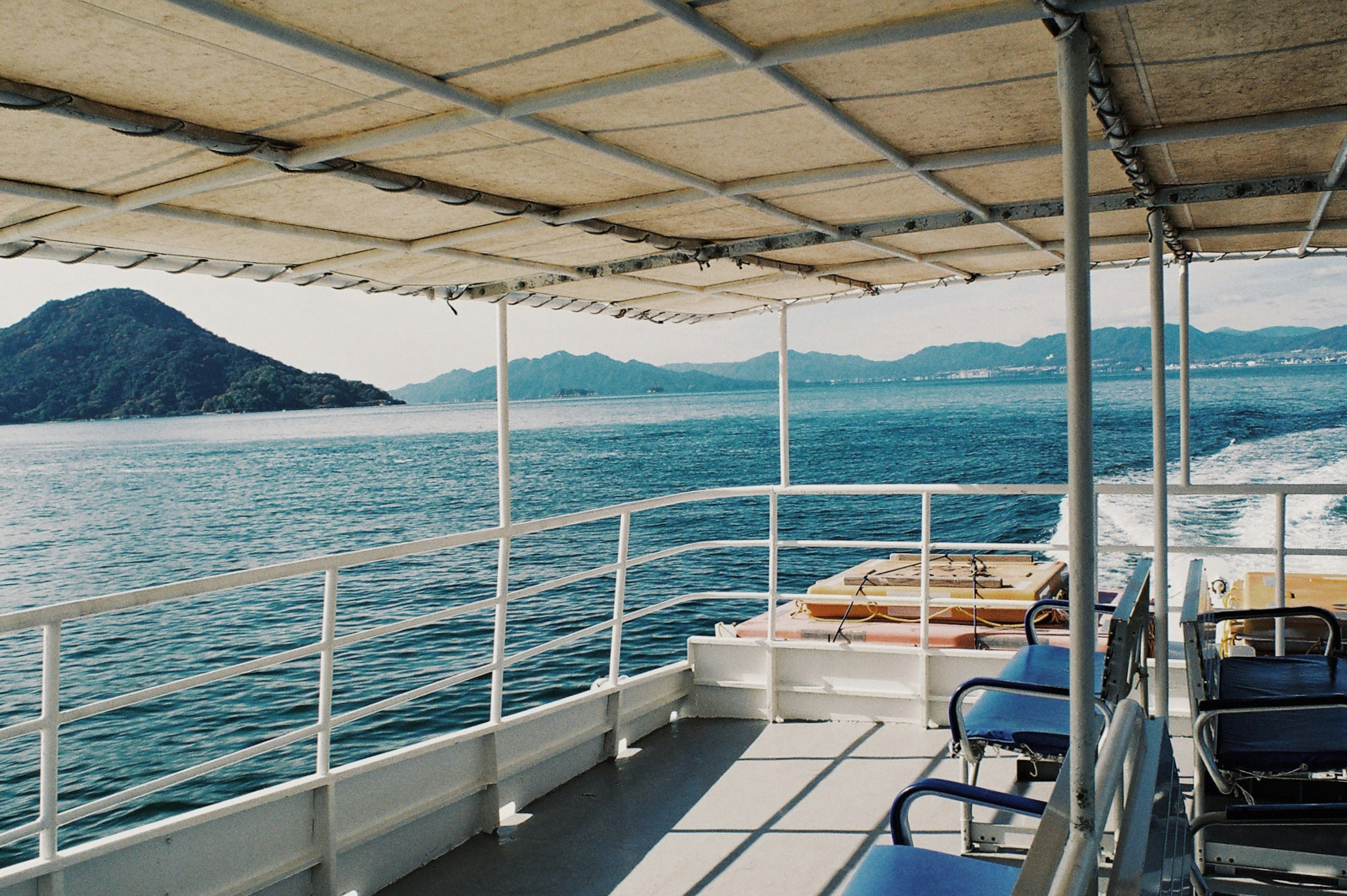 Cubierta de un barco con vista al mar tranquilo y montañas distantes