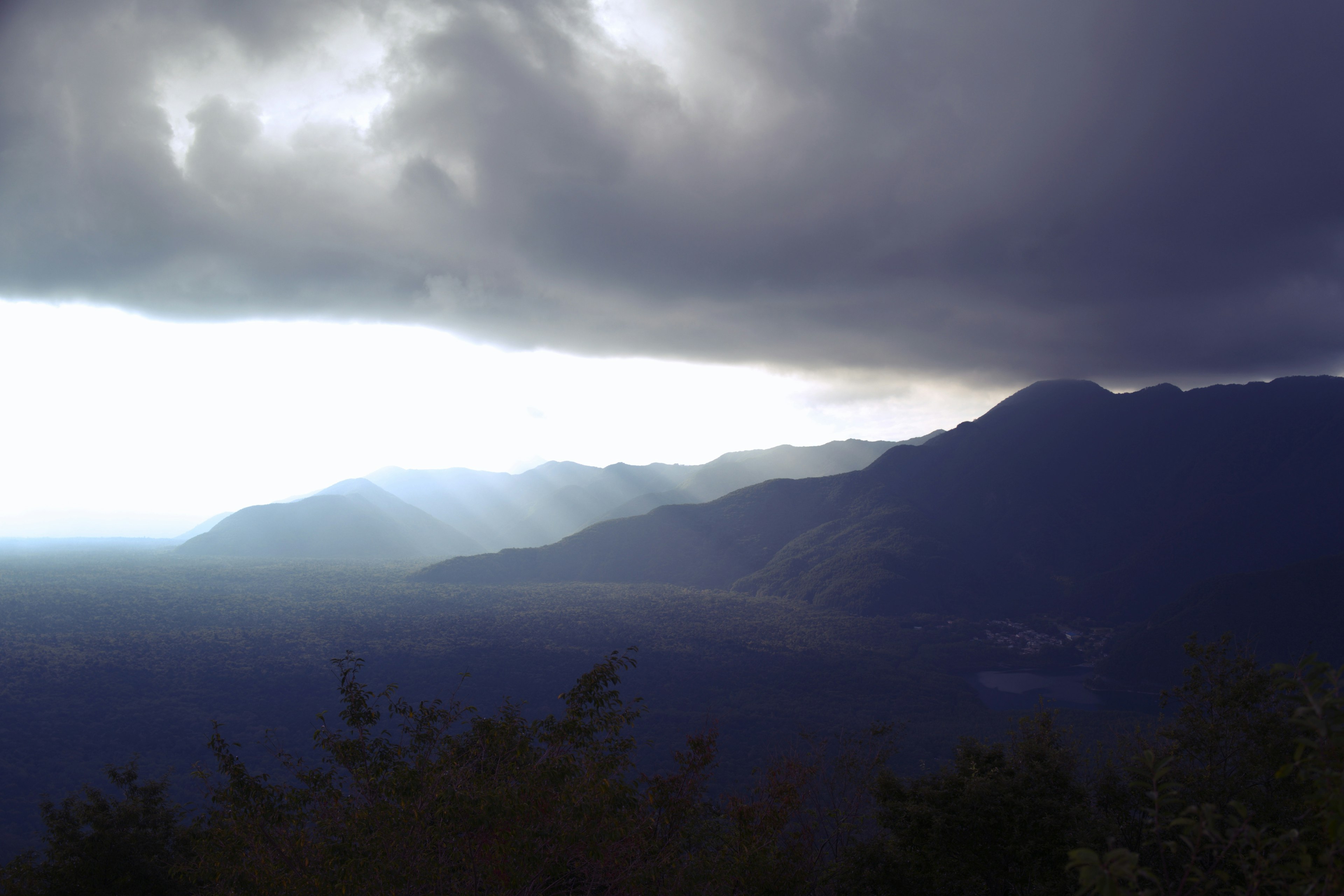 暗い雲に覆われた山々の景色と光の差し込み