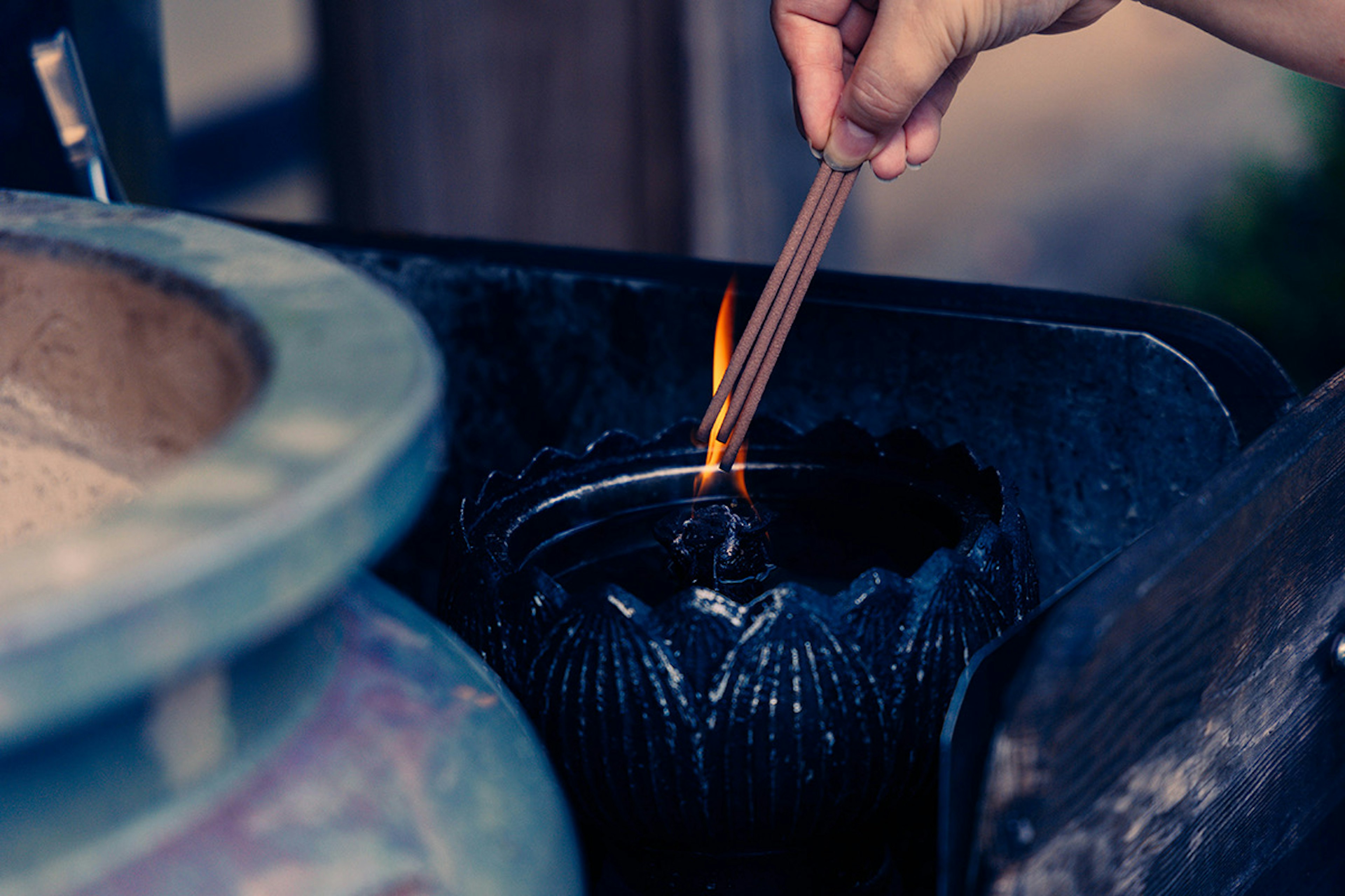 Hand placing an incense stick into a black container