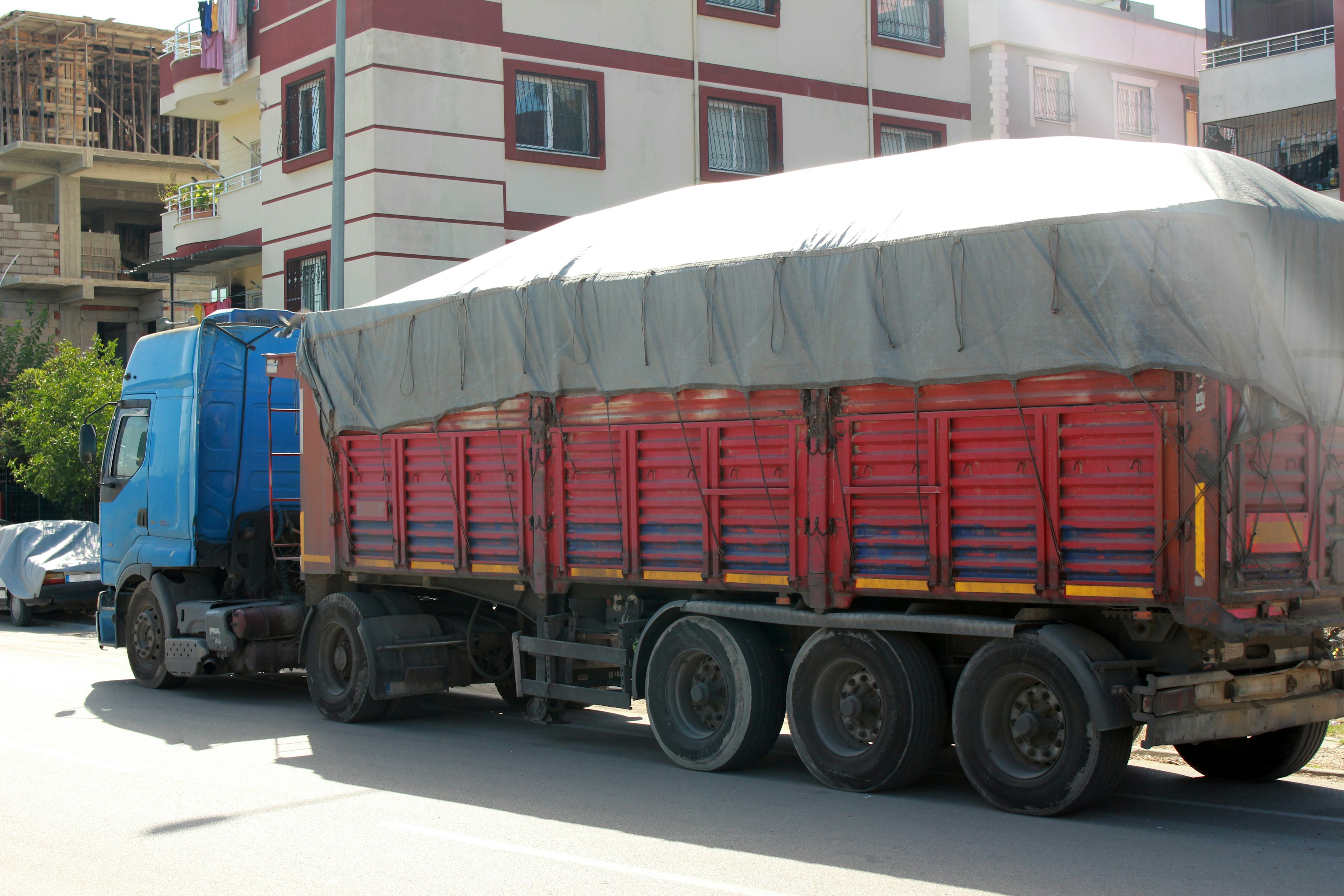 Blauer Lkw mit rotem Ladungstrailer, der auf der Straße geparkt ist