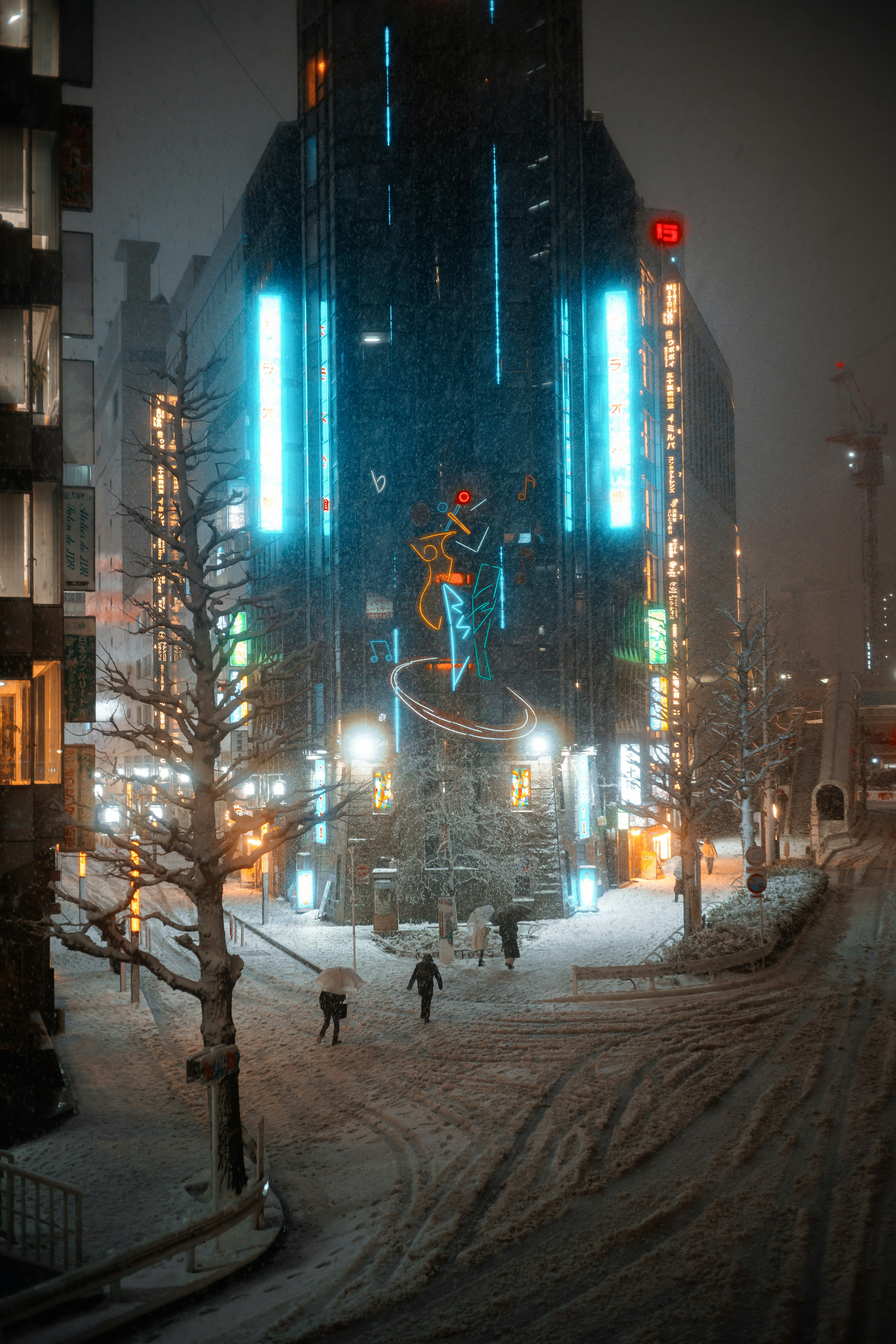 Snow-covered city scene featuring a blue neon building and people walking at night