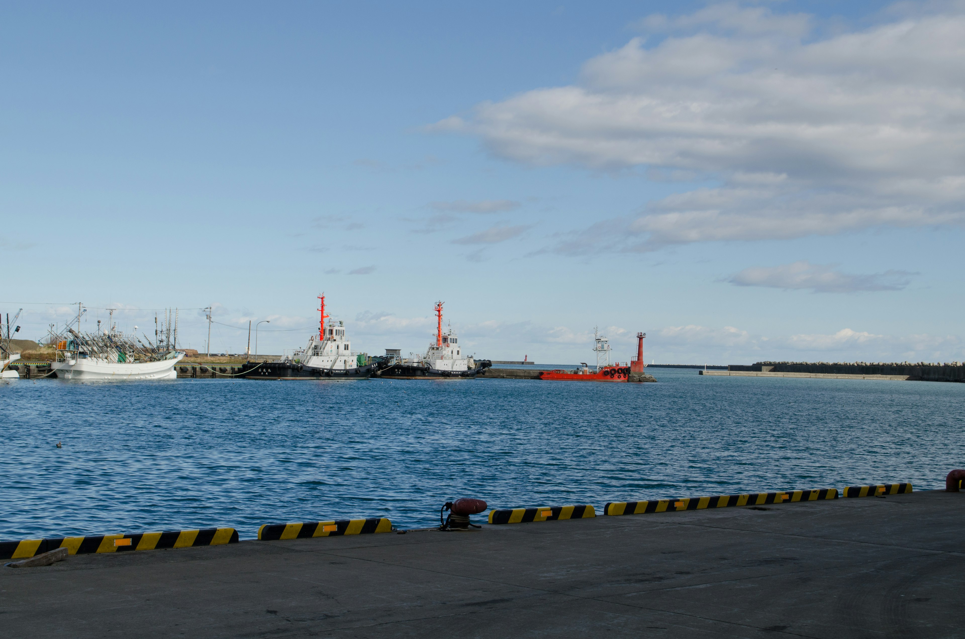 Harbor scene with fishing boats and cargo ship blue sea and sky