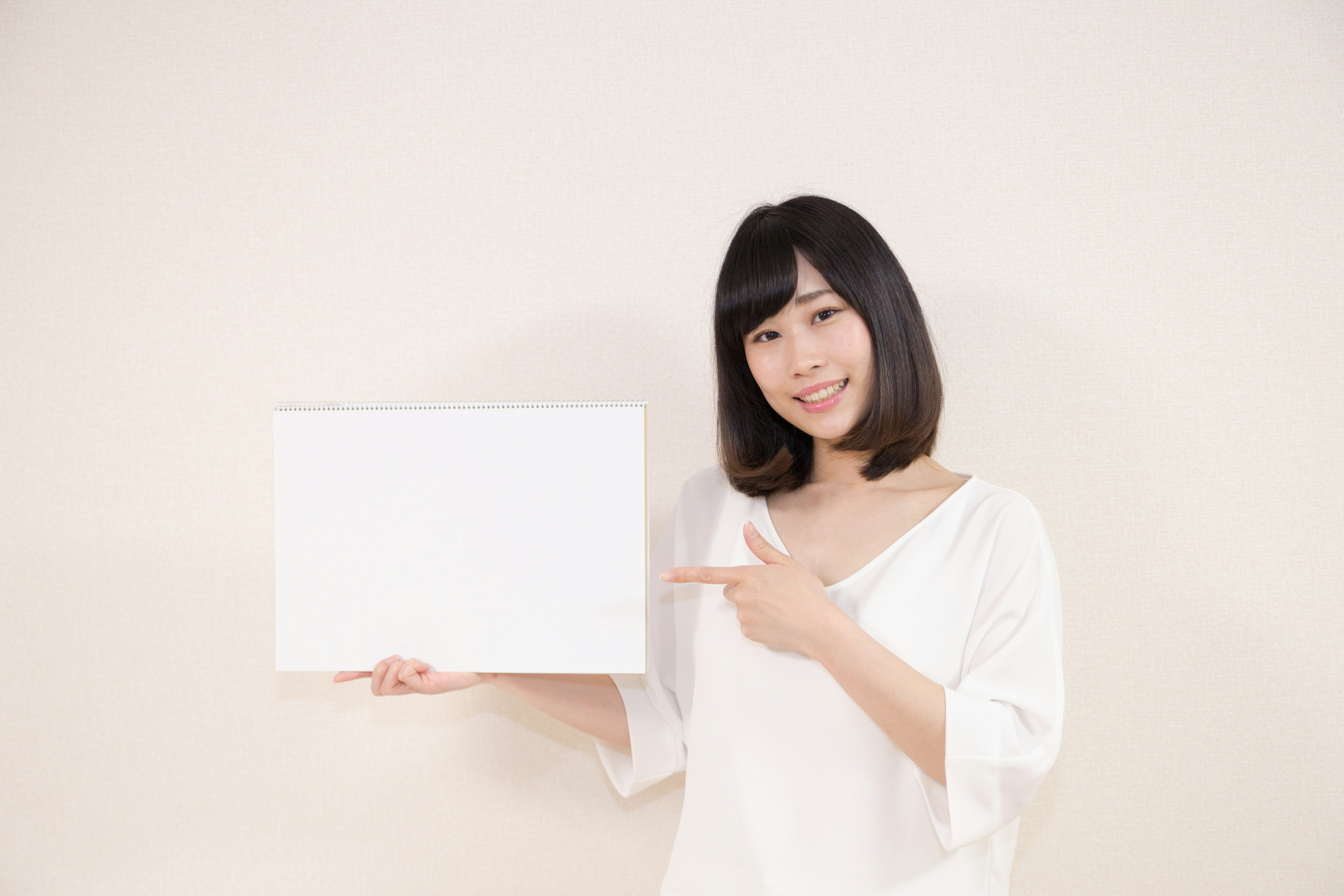 Woman holding a blank white board in front of a light background