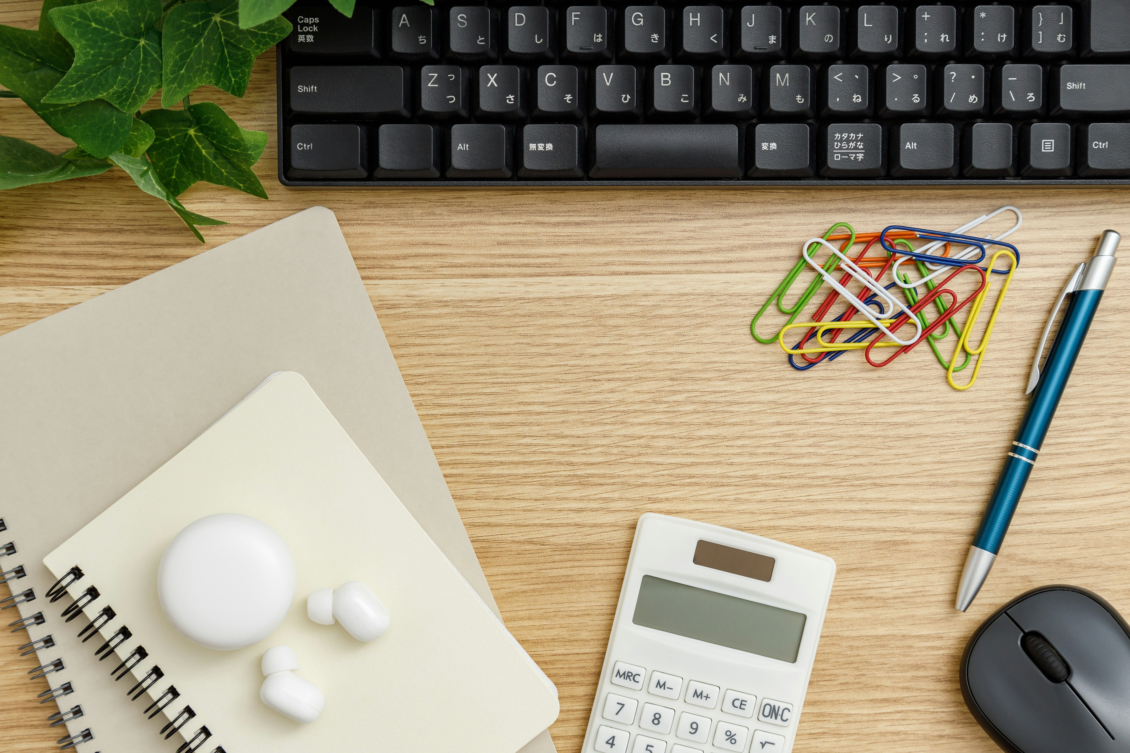 Schwarze Tastatur auf einem Holztisch mit Schreibwaren und Taschenrechner