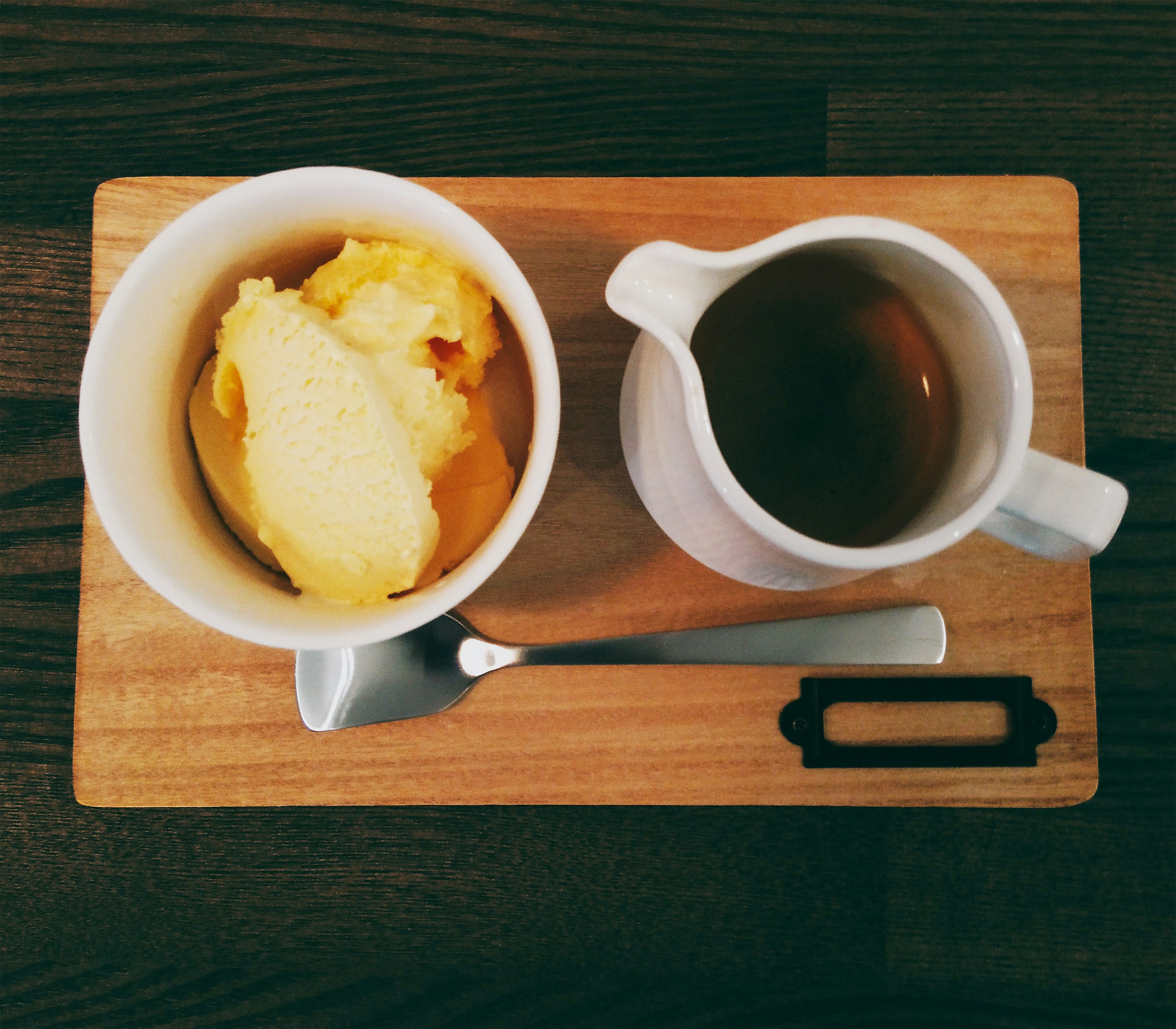 Una bandeja de madera con un tazón de helado y una taza de té