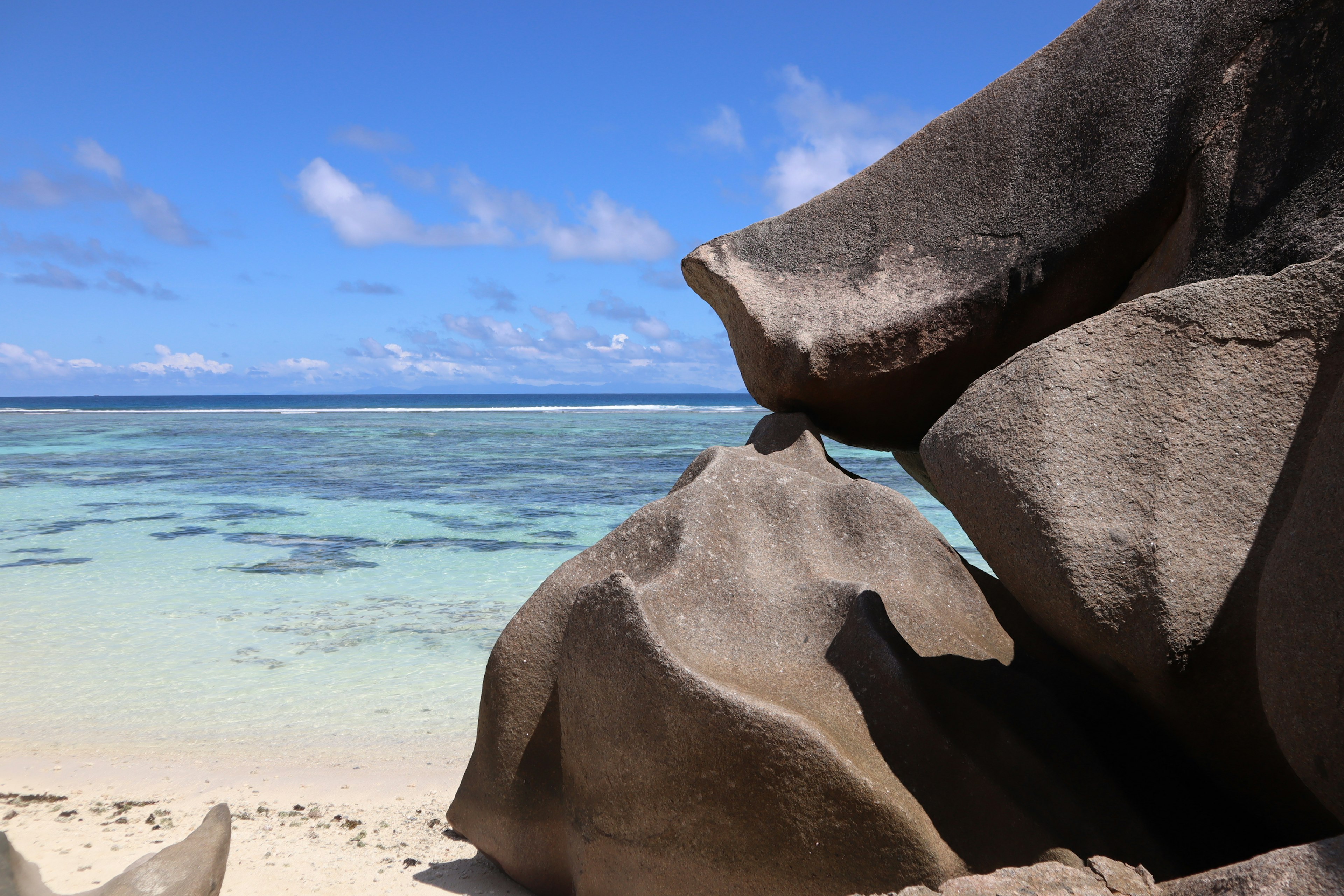 Formasi batu unik dengan latar belakang laut biru dan pantai berpasir putih