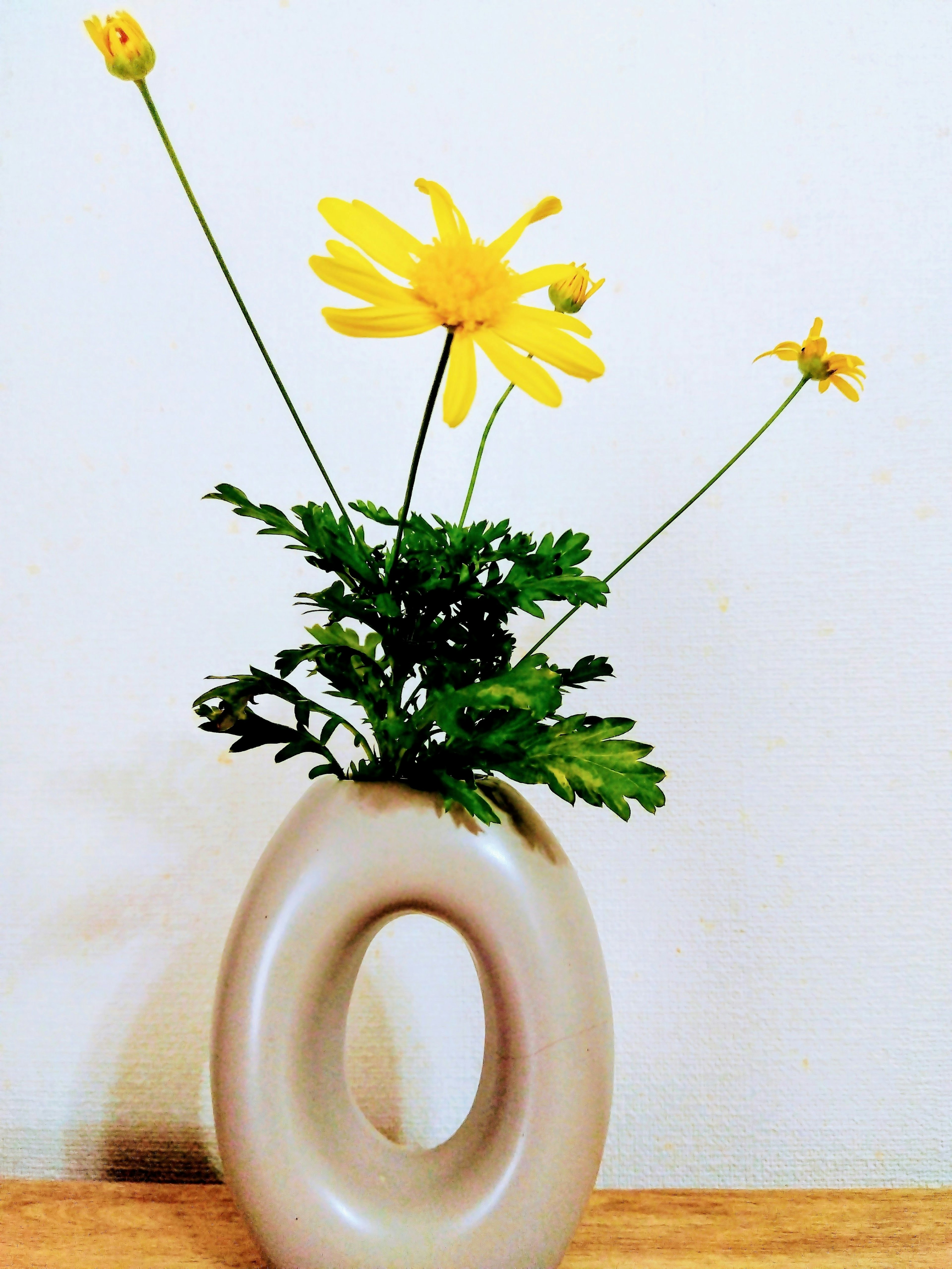 Vase hình độc đáo với hoa vàng và lá xanh