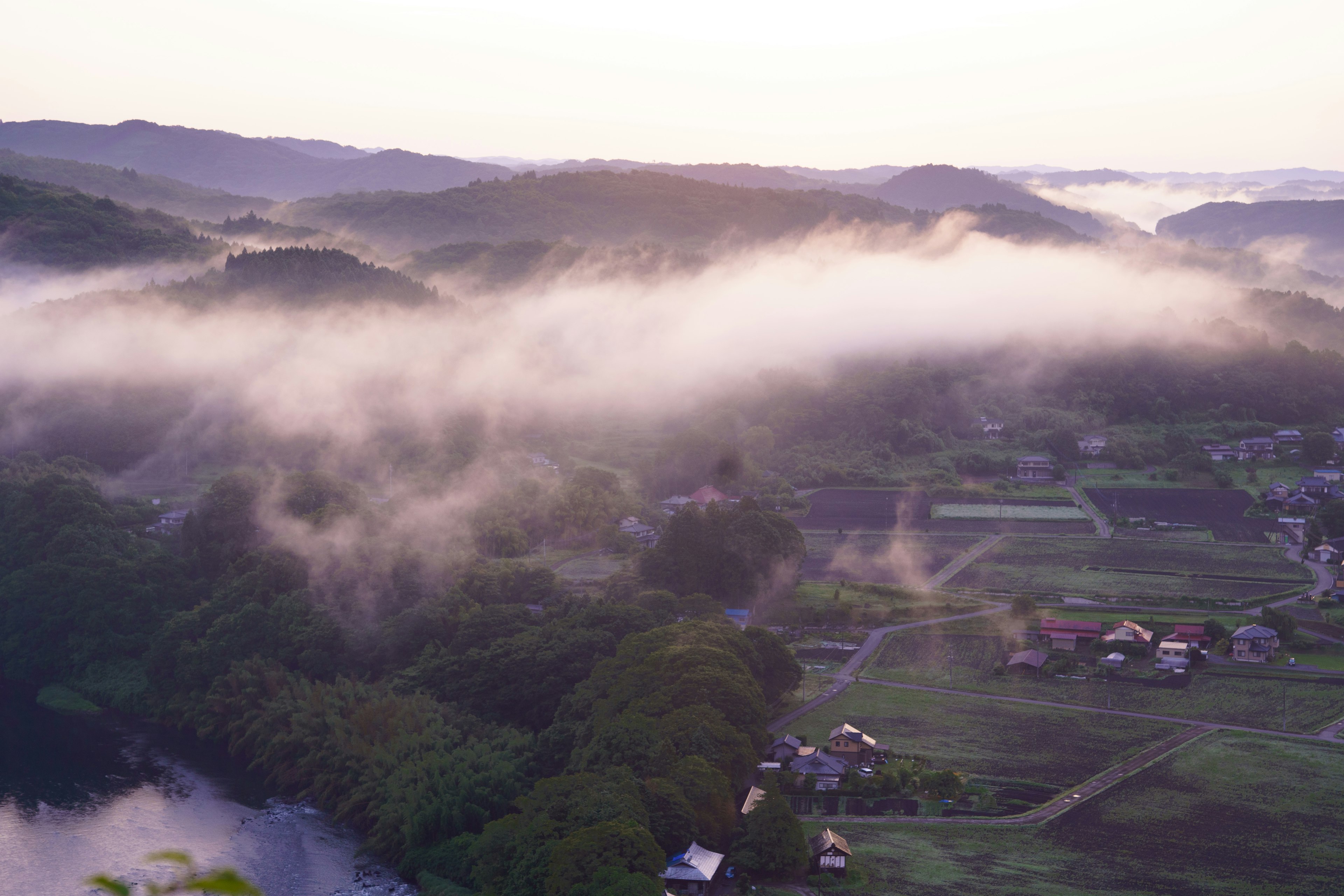 霧に包まれた山々と田園風景の美しい朝の風景