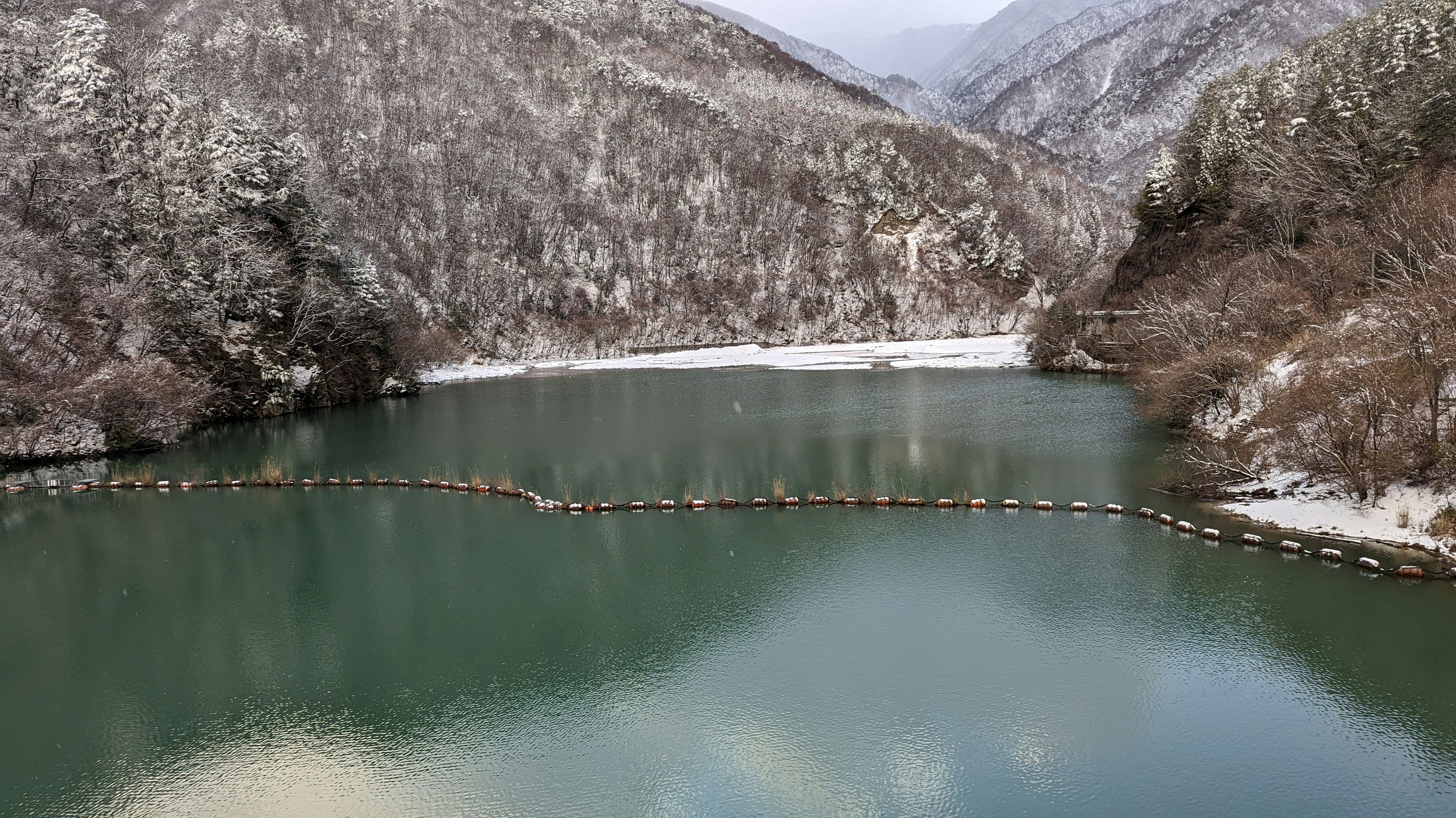 雪に覆われた山々に囲まれた静かな湖の風景