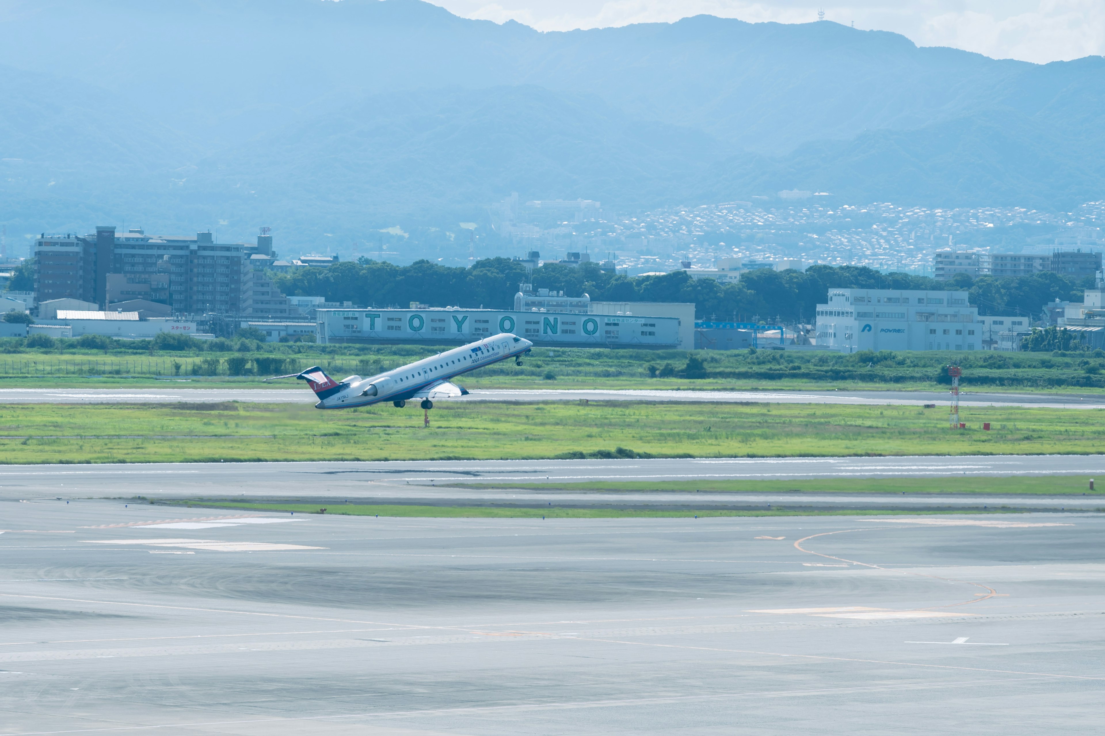 Aereo in decollo sotto un cielo blu con montagne sullo sfondo