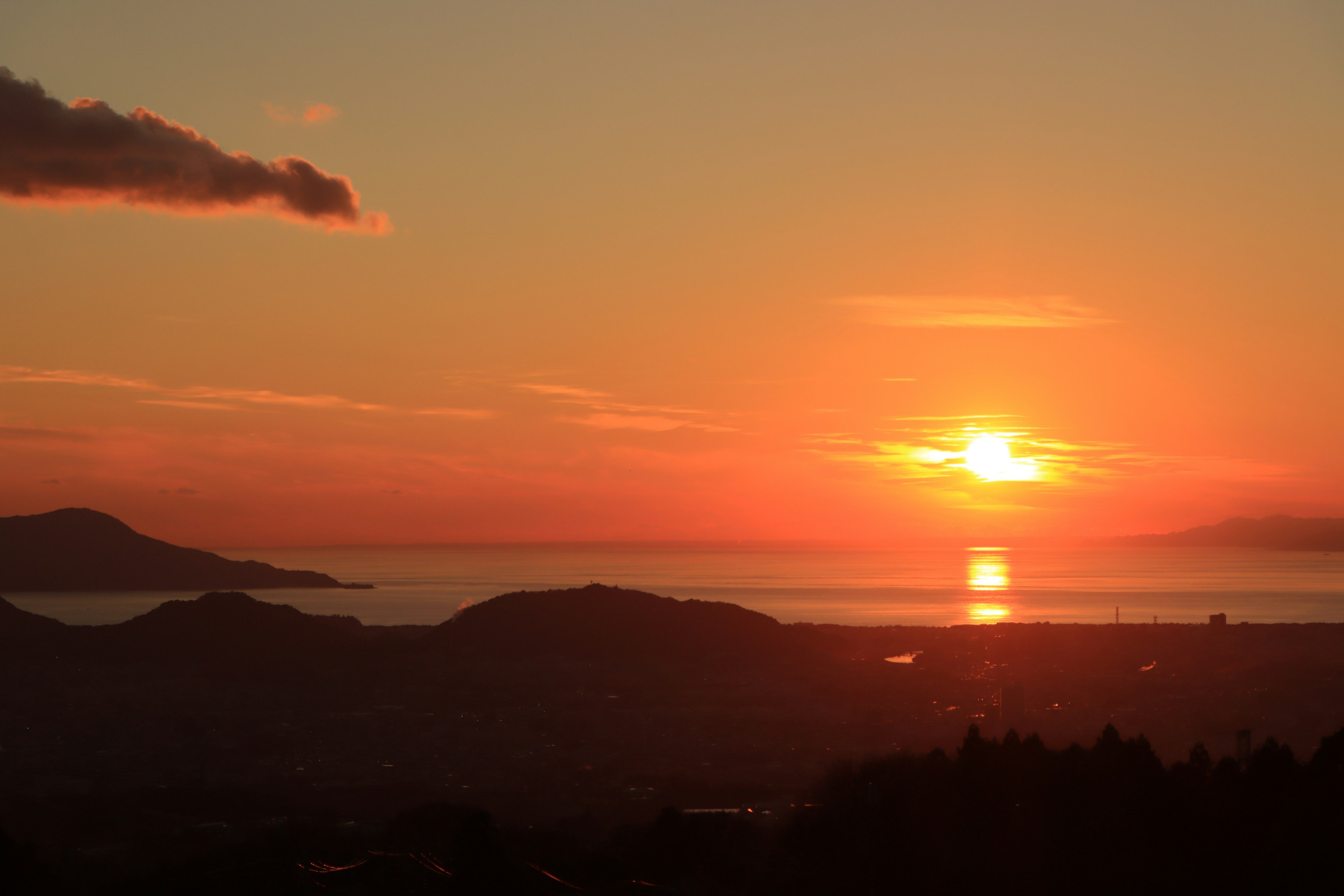 Schöne Landschaft des Sonnenuntergangs über dem Meer mit Bergen und Wolken