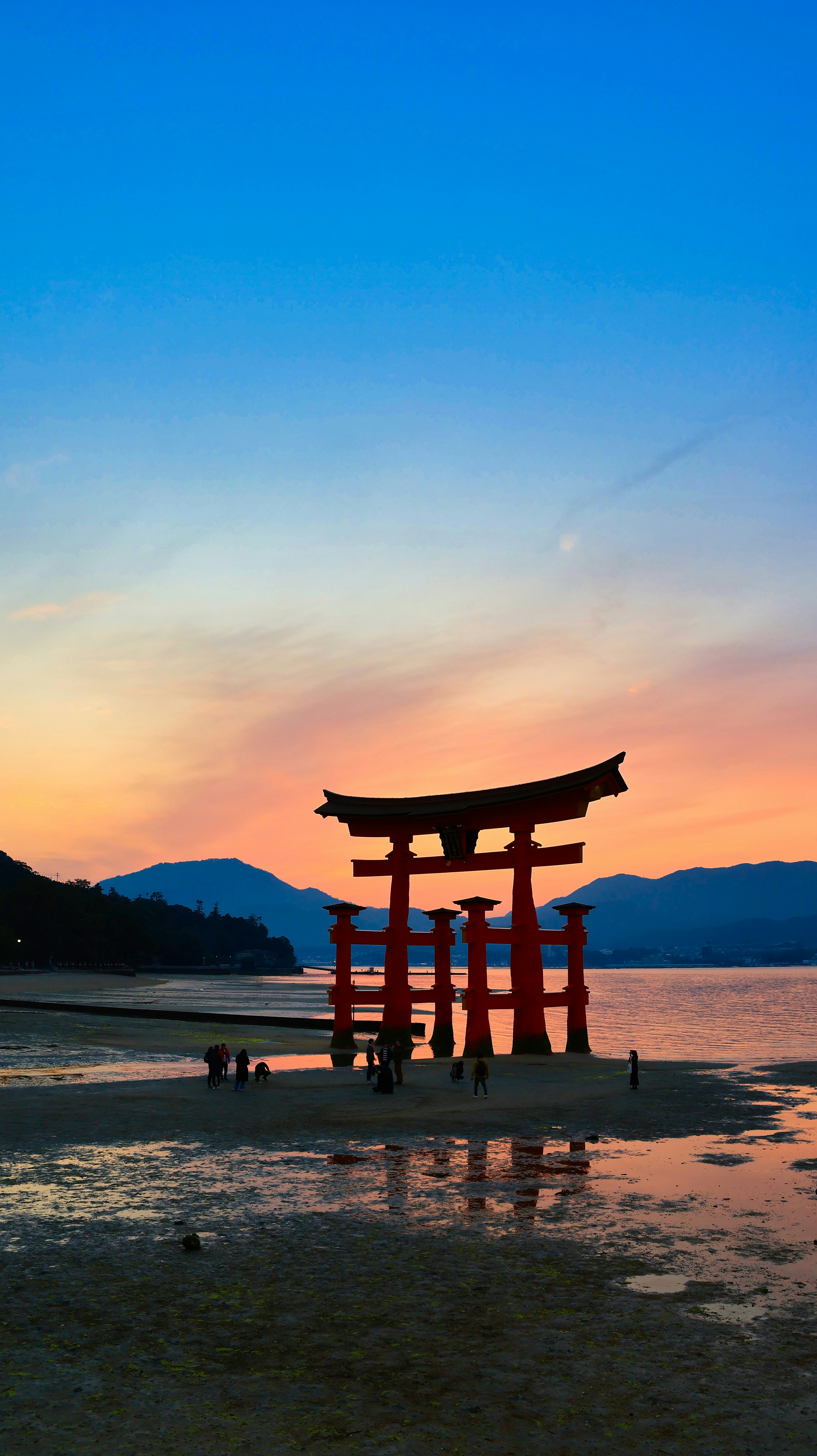 Puerta torii roja de pie en el mar durante un hermoso atardecer