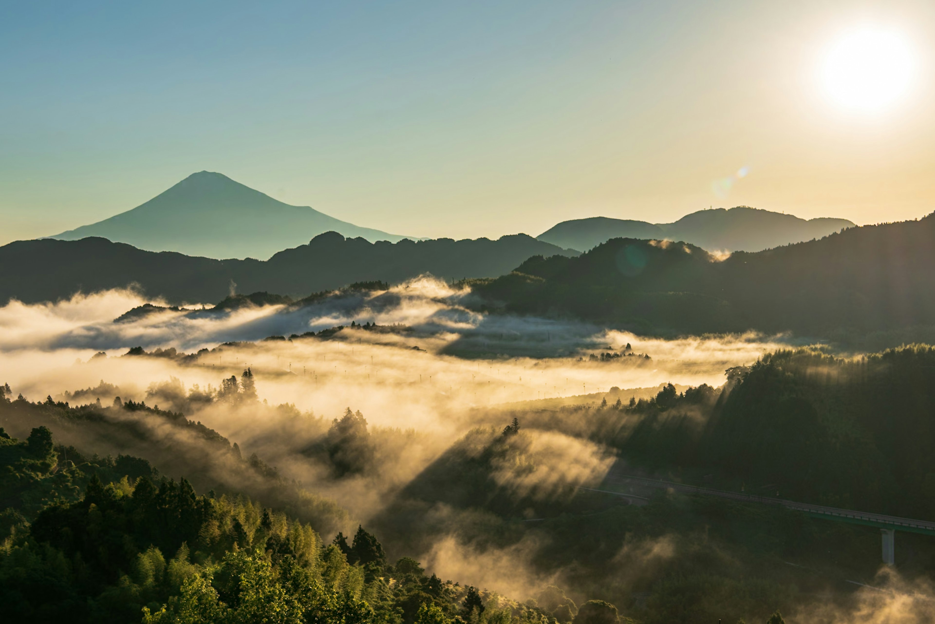 Scenic view of mountains and valleys shrouded in mist with sunrise illuminating the landscape