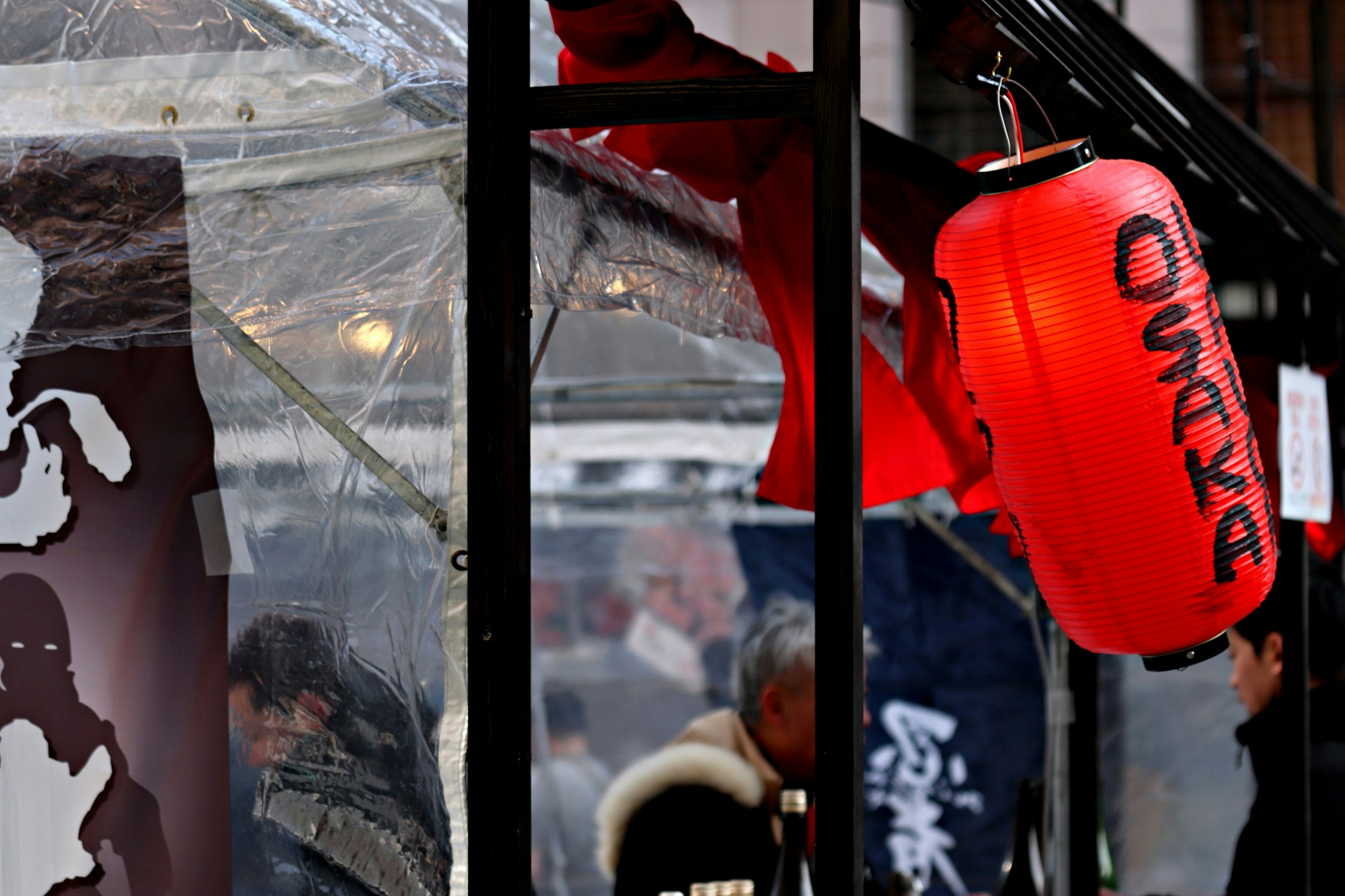 Lanterna rossa appesa con Osaka scritto su di essa in un contesto di bancarella di cibo