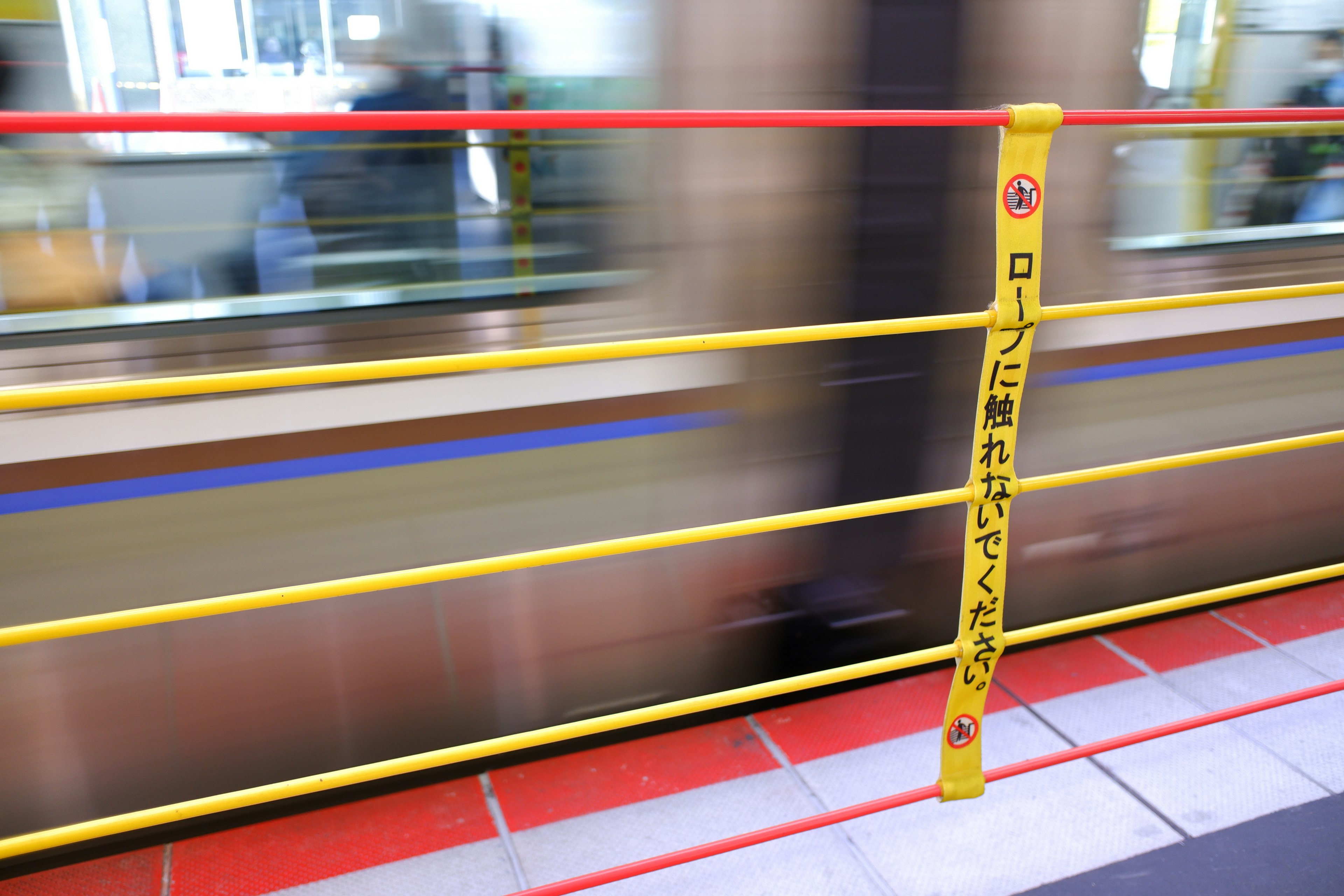 Image of a moving train with red and yellow safety barriers