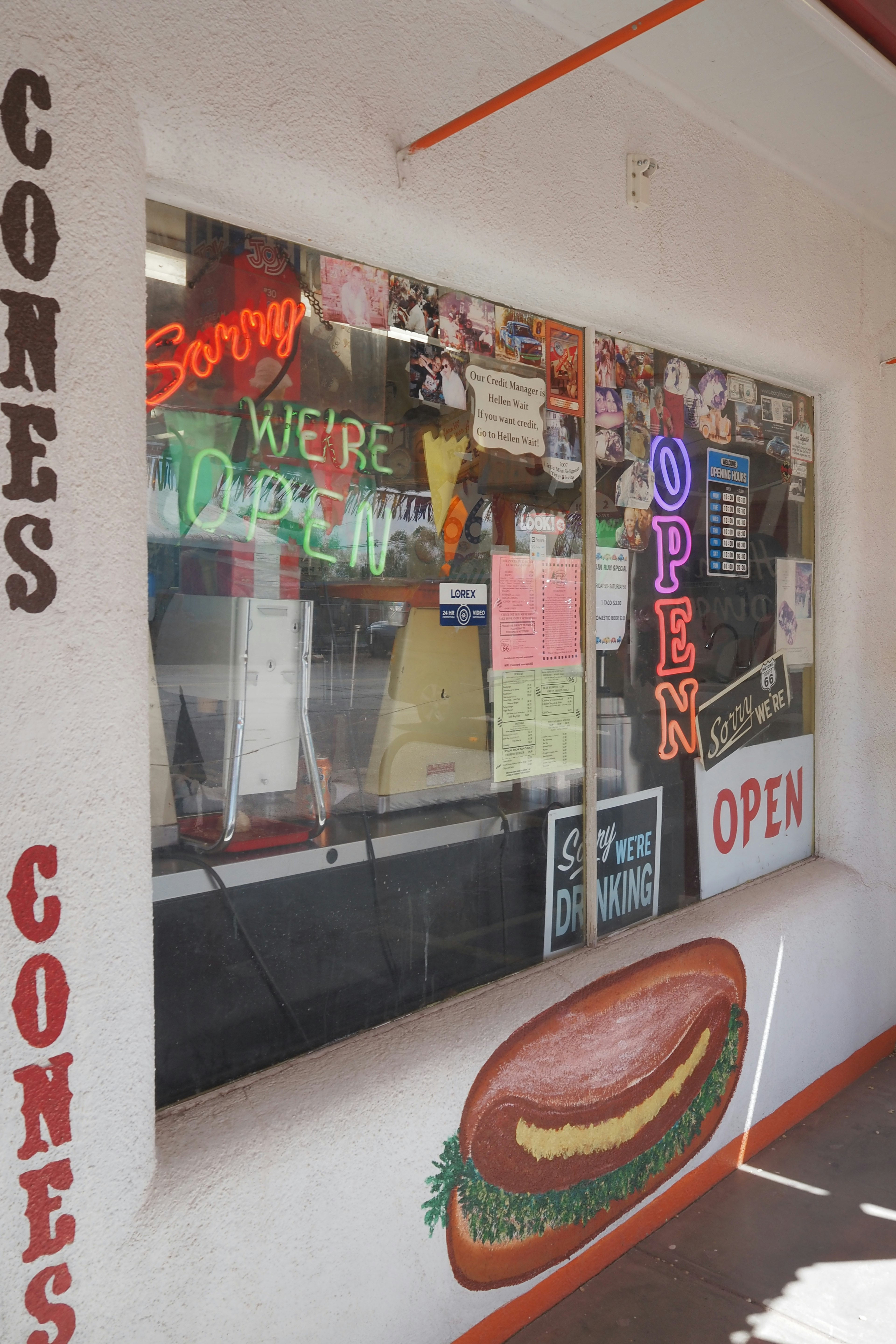 Ventana de tienda con letreros coloridos y luces de neón abiertas