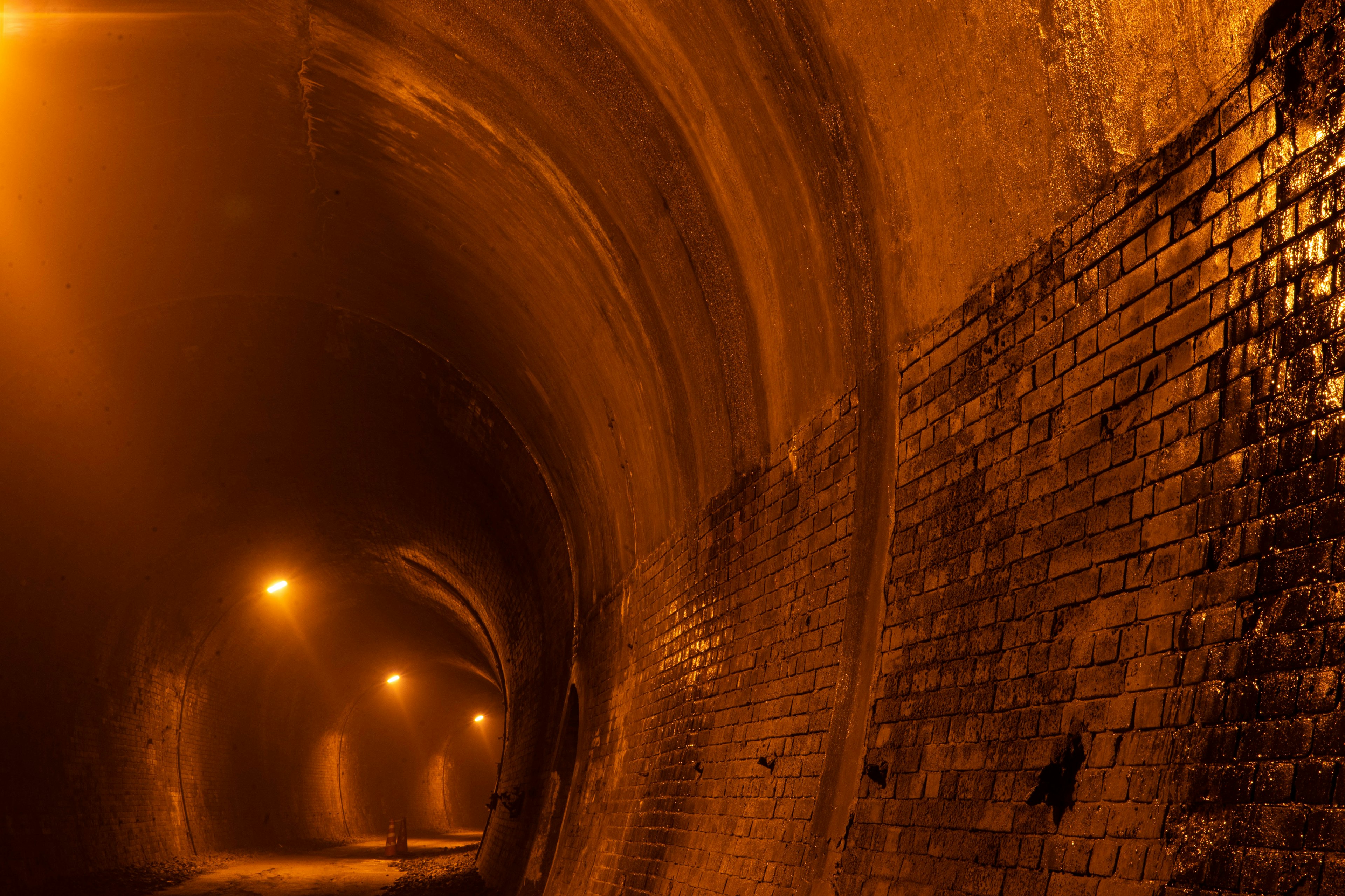 Inneres eines dunklen Tunnels, beleuchtet von orangefarbenen Lichtern