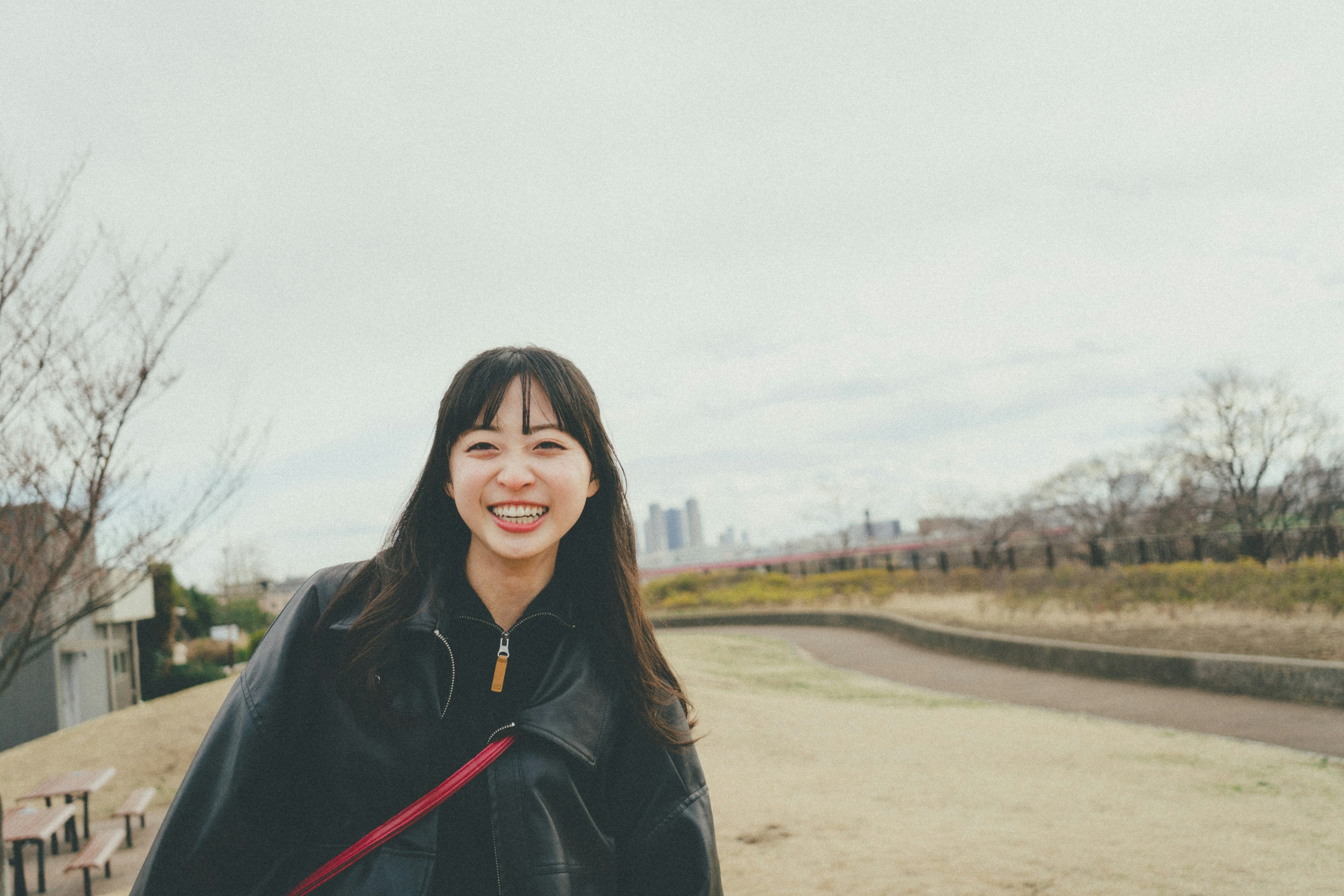 Mujer sonriente de pie en un parque con un paisaje urbano de fondo