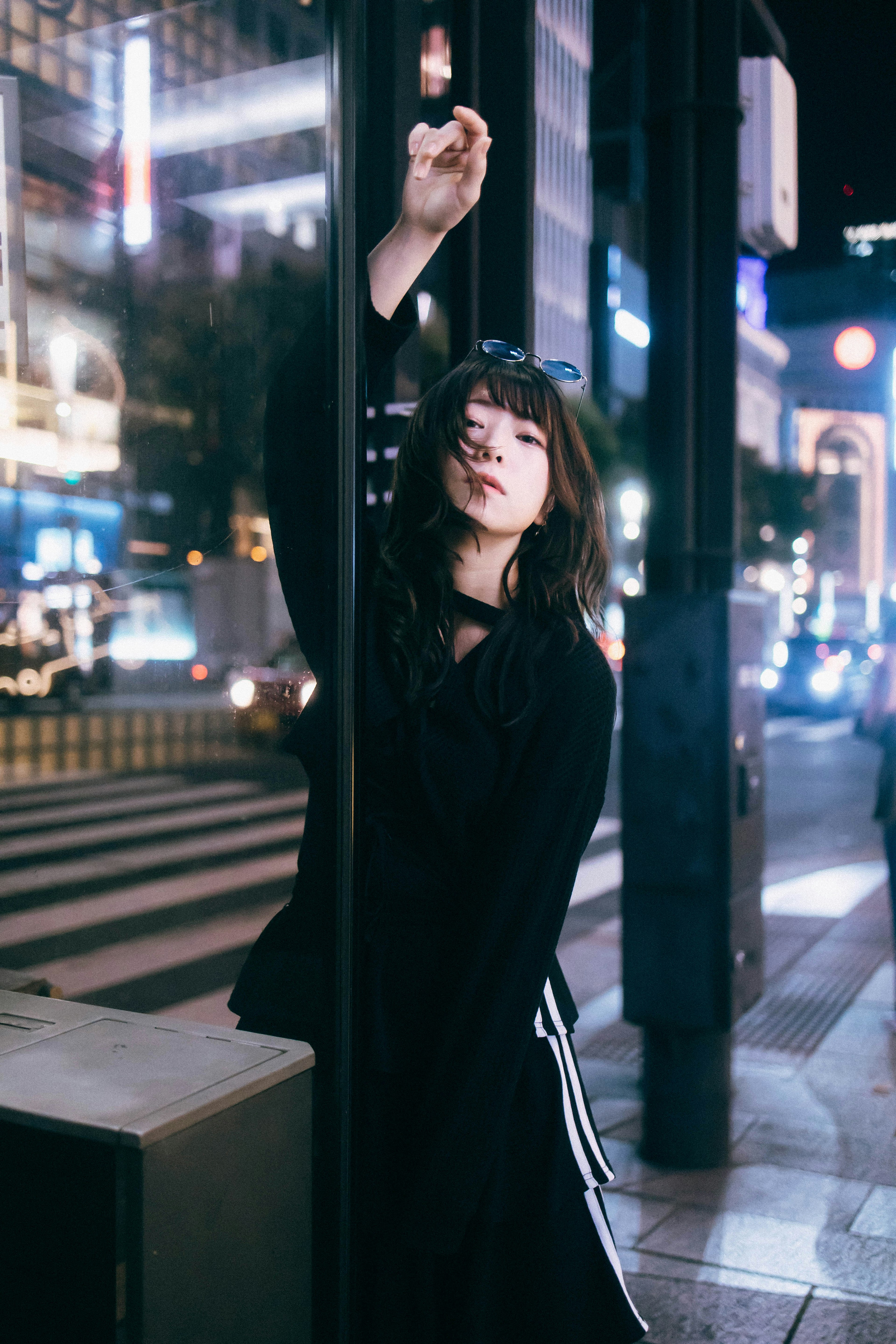 A woman leaning against a pole in a city at night