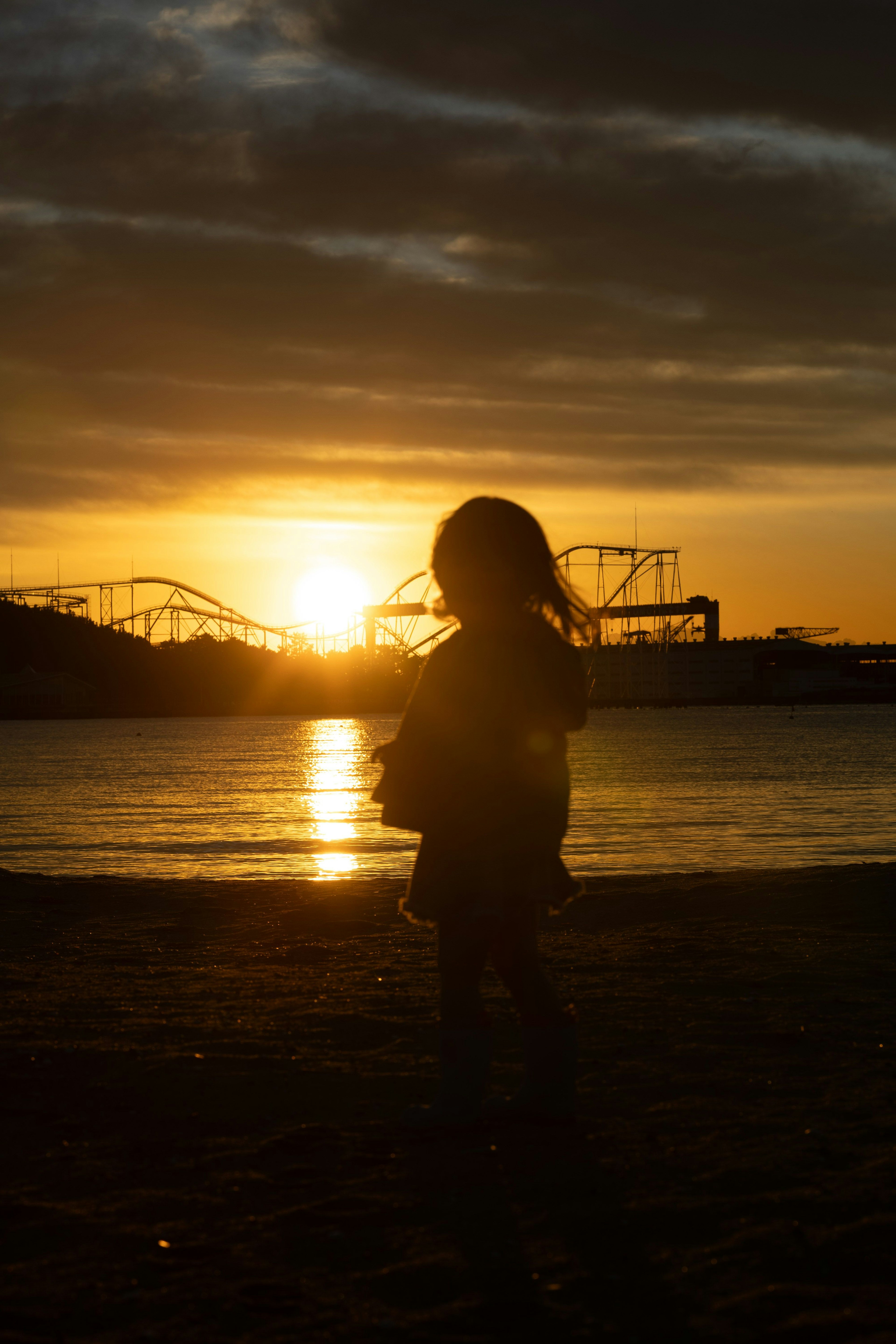 Silhouette d'un enfant au coucher de soleil avec un parc d'attractions en arrière-plan