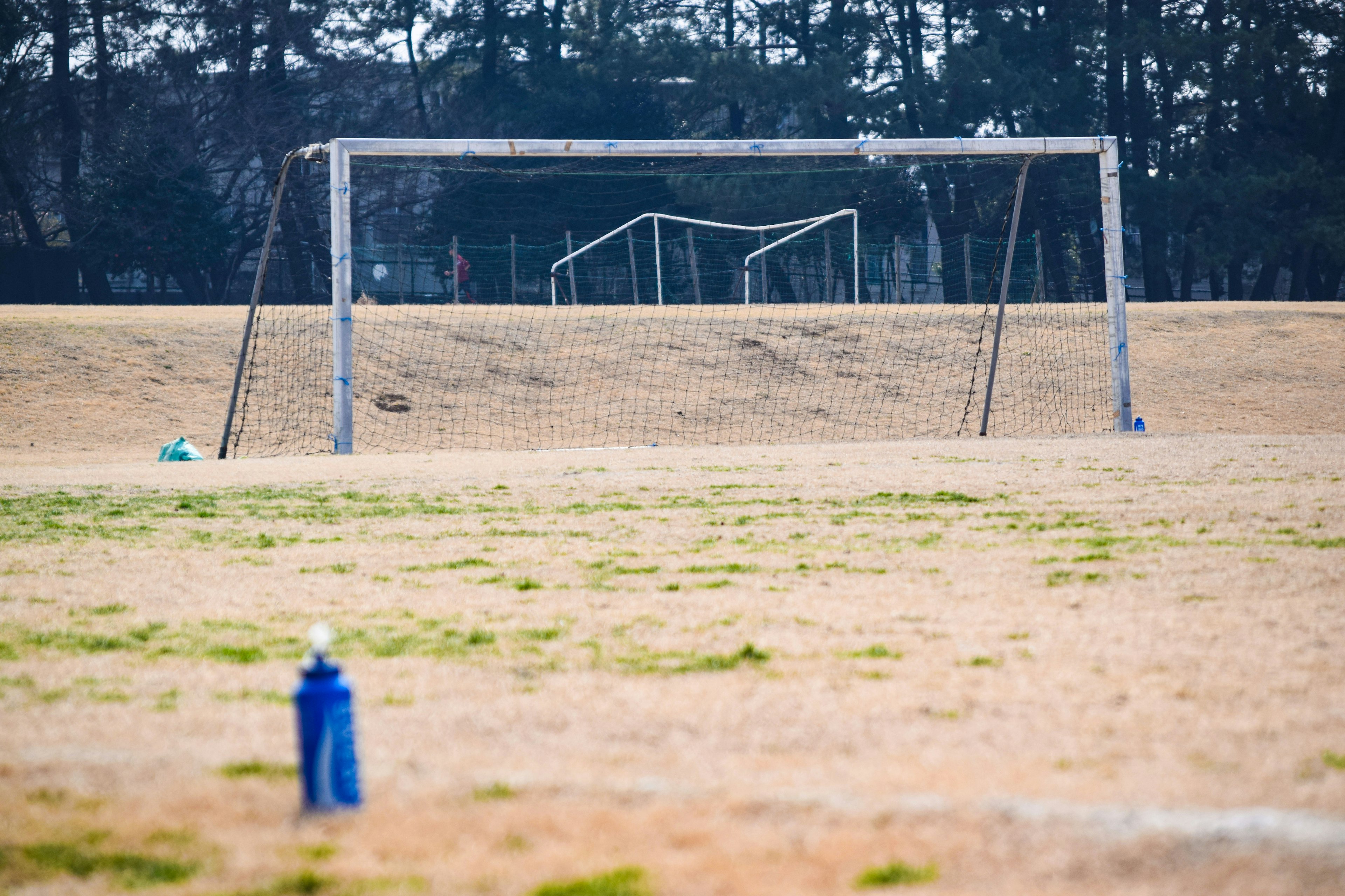 Ampio campo con una porta da calcio sullo sfondo una bottiglia d'acqua in primo piano