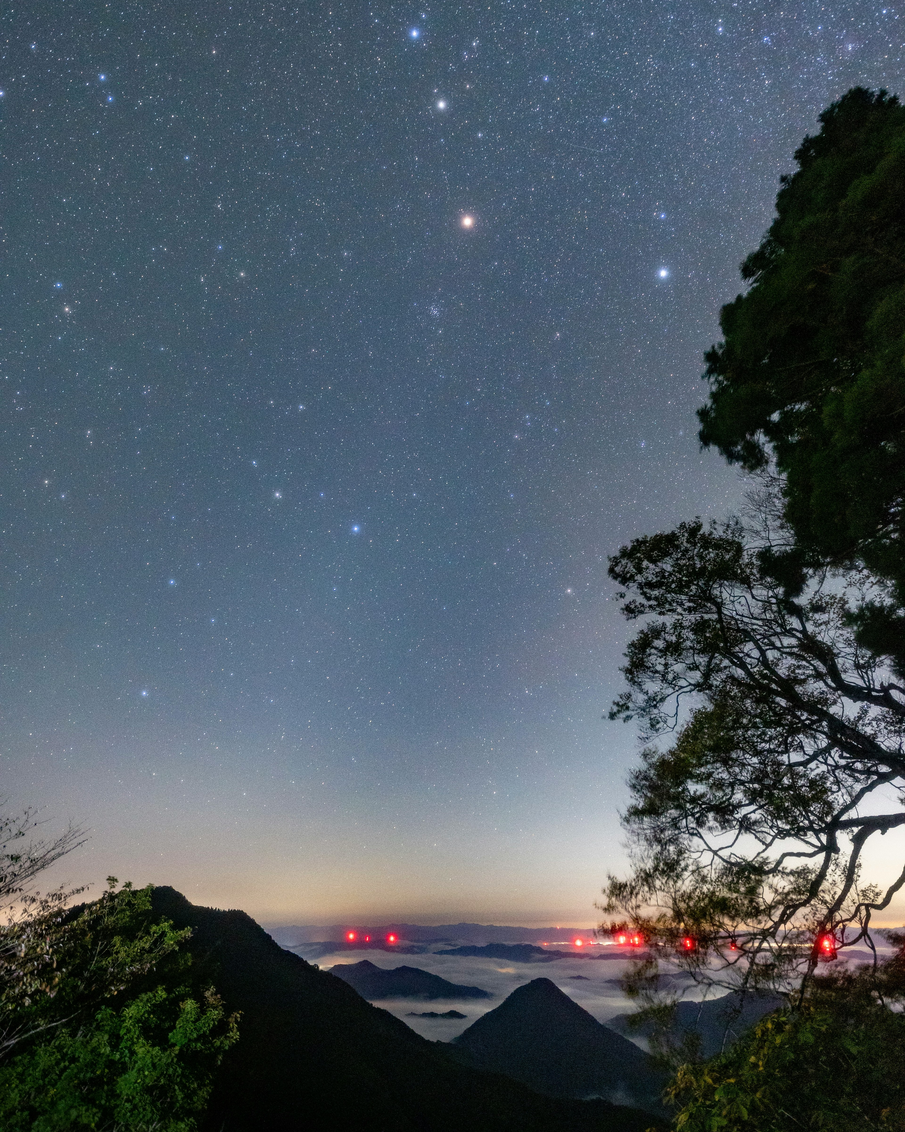 星空と山々の景色に赤い灯りが見える