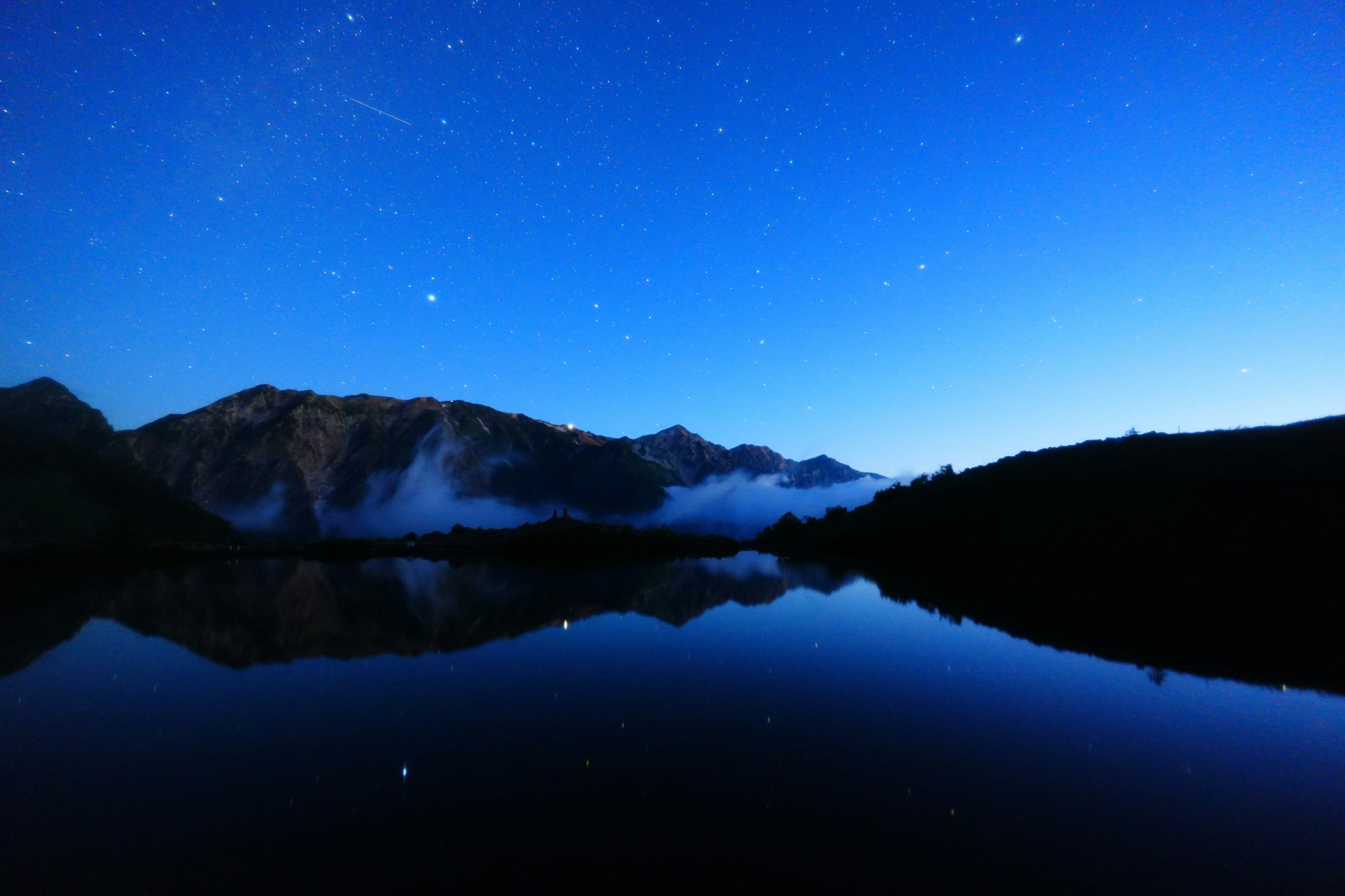 Paesaggio sereno di lago con cielo stellato e riflessi montani