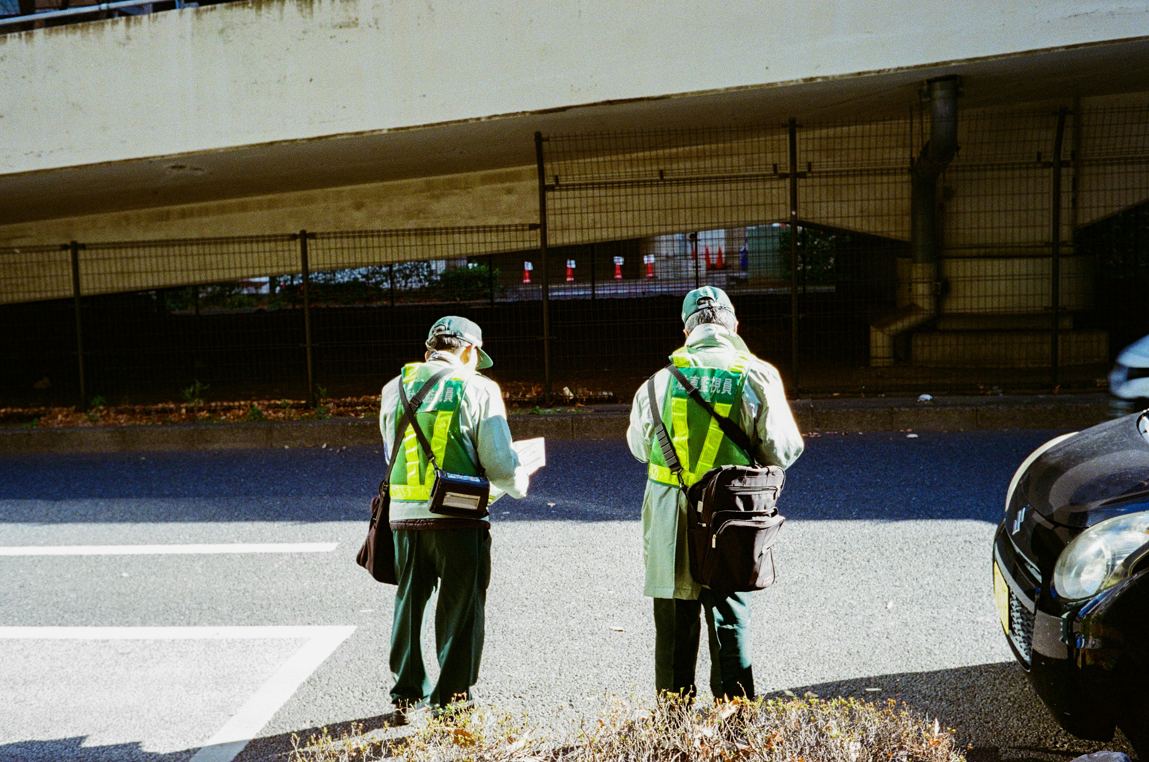 Dos trabajadores con chalecos reflectantes verdes de pie cerca de una carretera