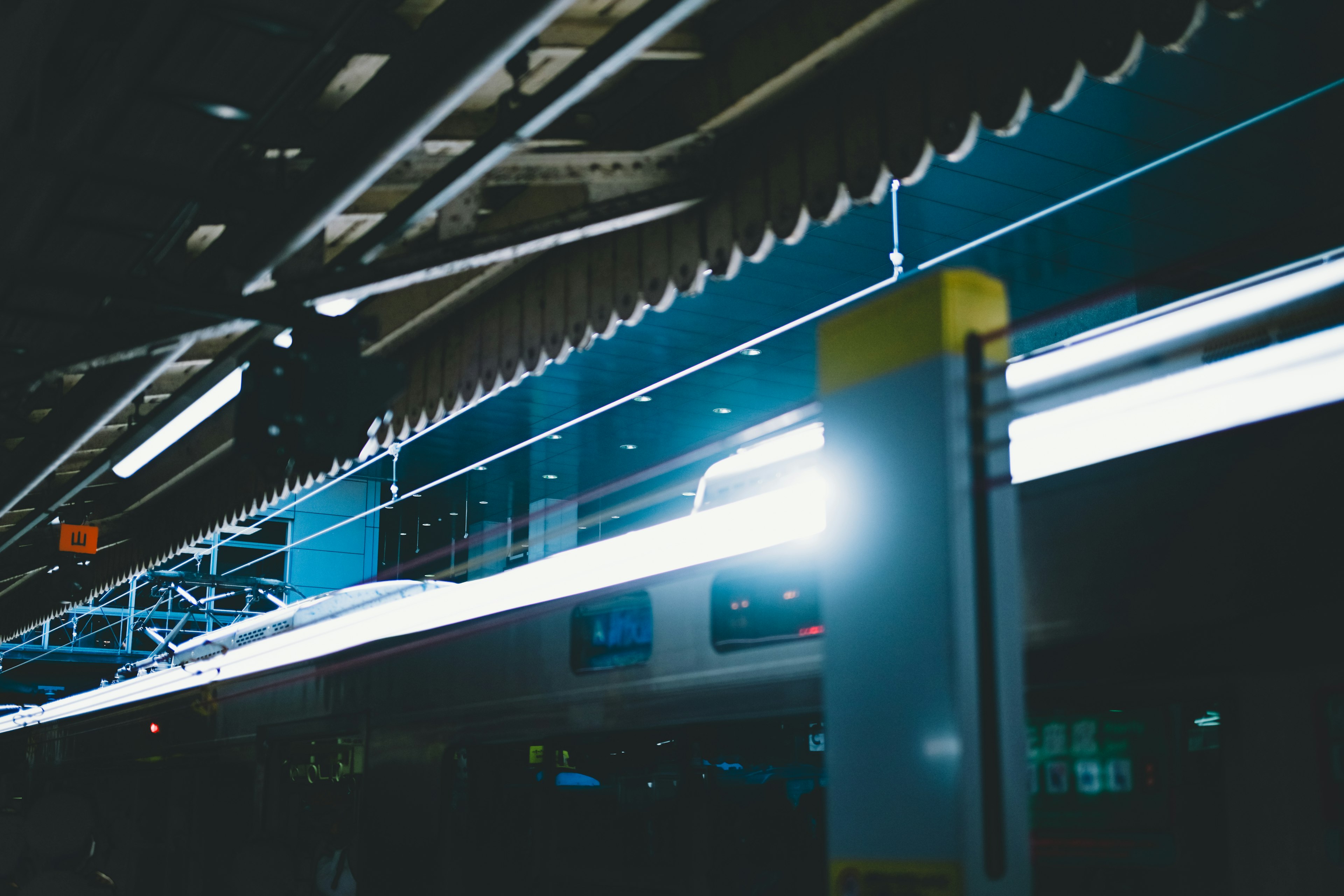 Interior of a train station with intersecting blue and white lights against a dark background