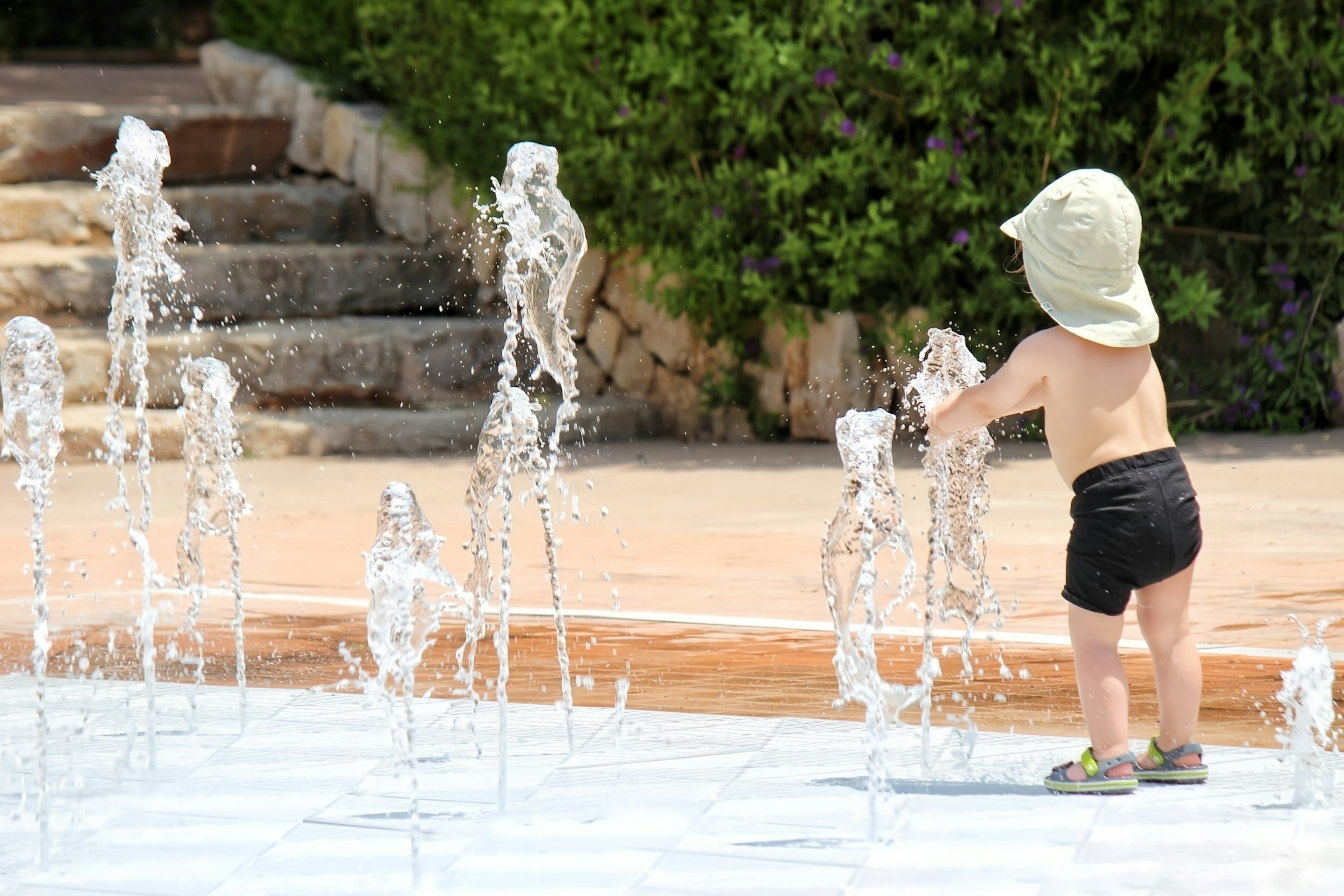 Un bambino piccolo che gioca in una fontana d'acqua