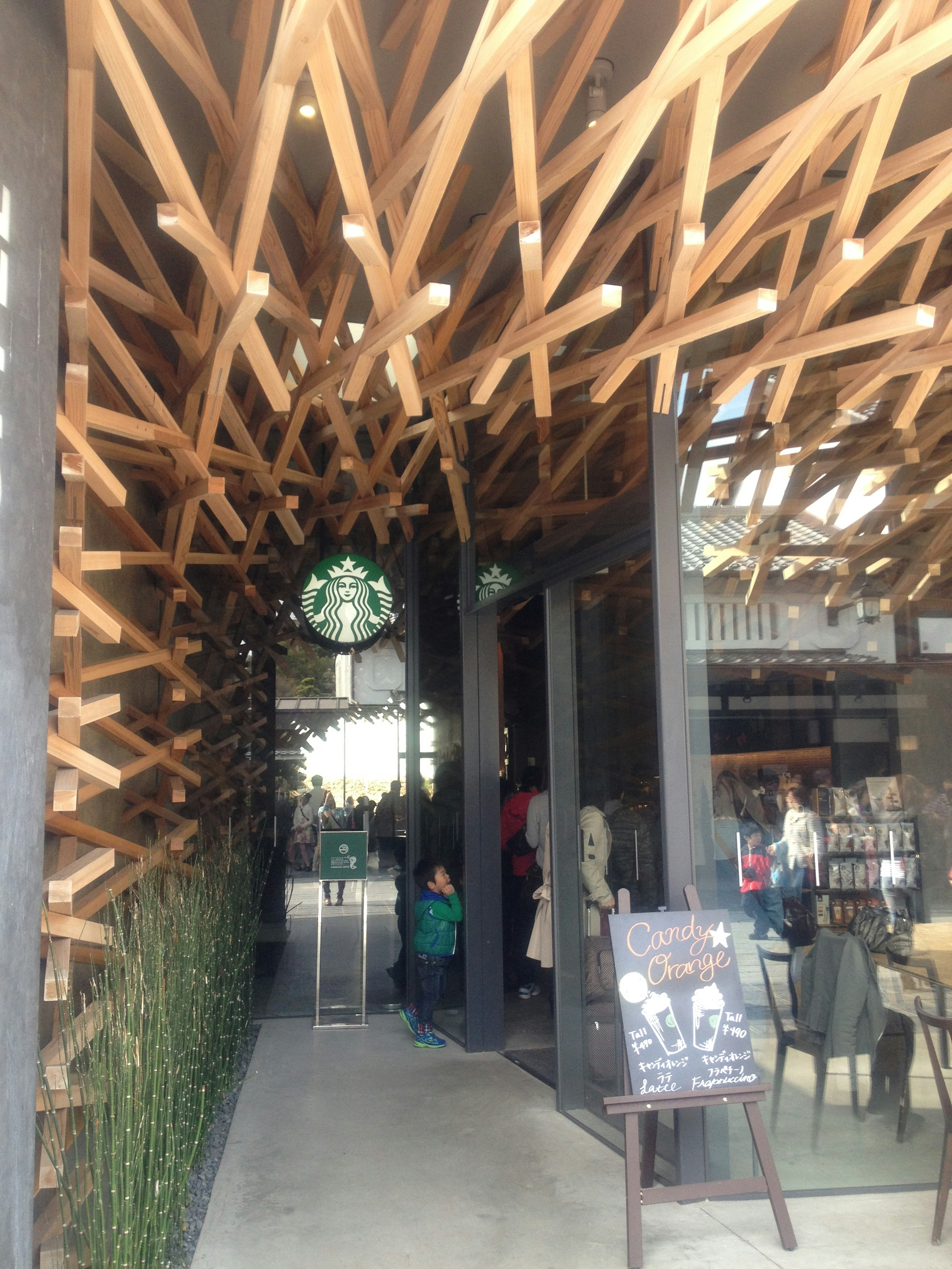 Unique entrance of Starbucks featuring wooden design and greenery