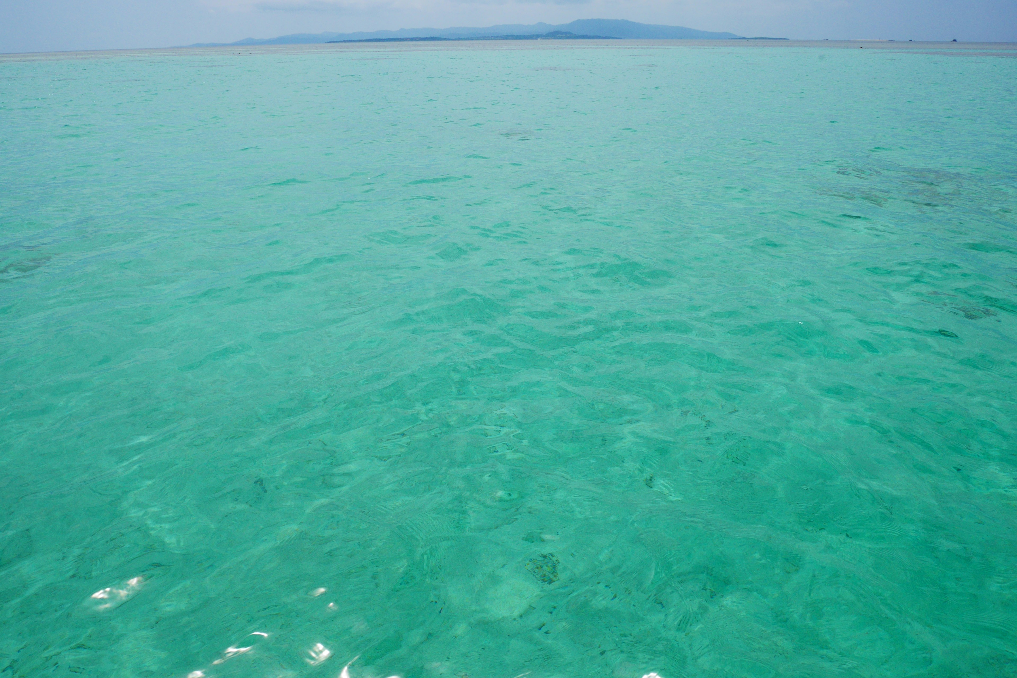 Agua turquesa cristalina con una isla a lo lejos